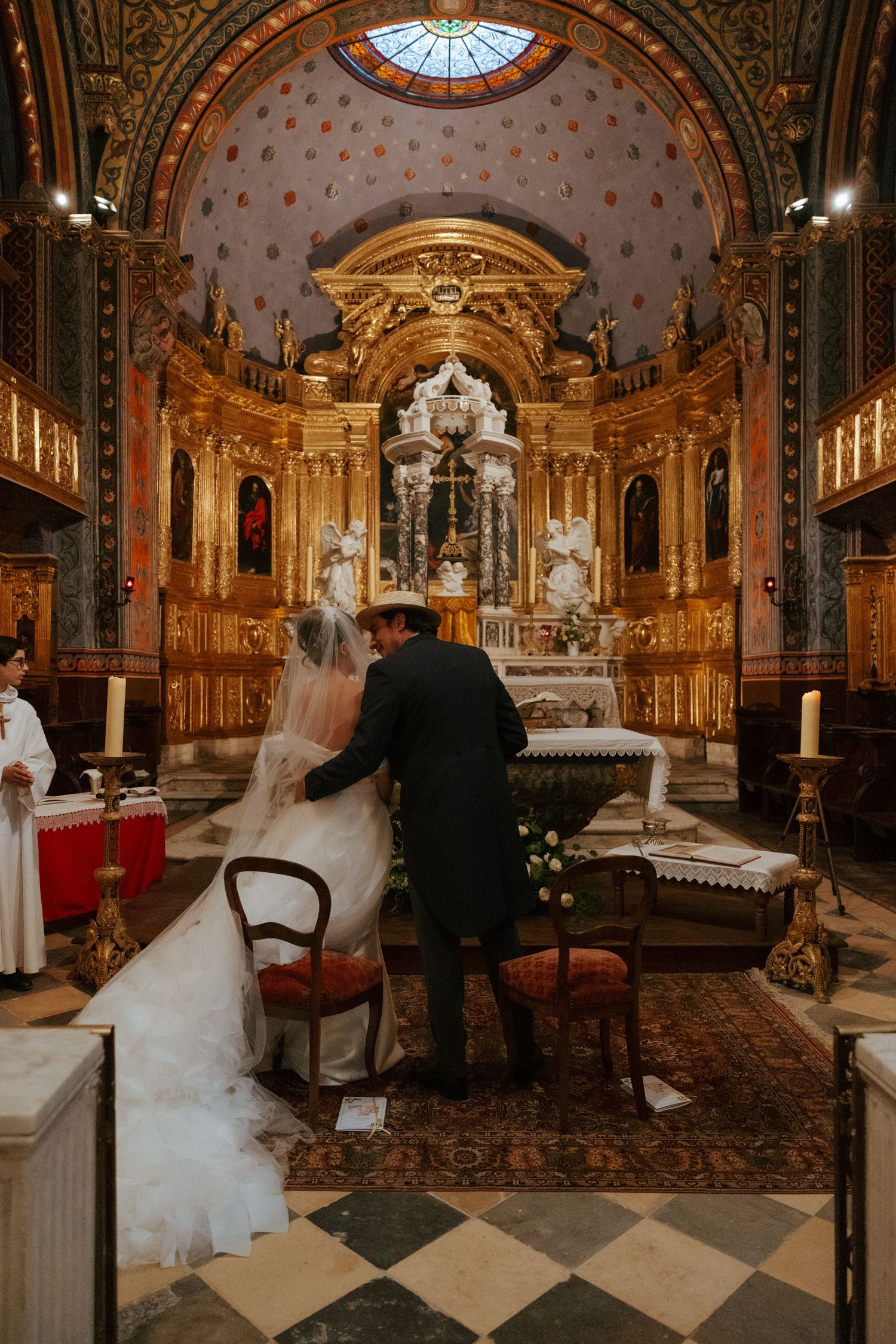Wedding ceremony in an opulent gold-decorated church with baroque architectural details.