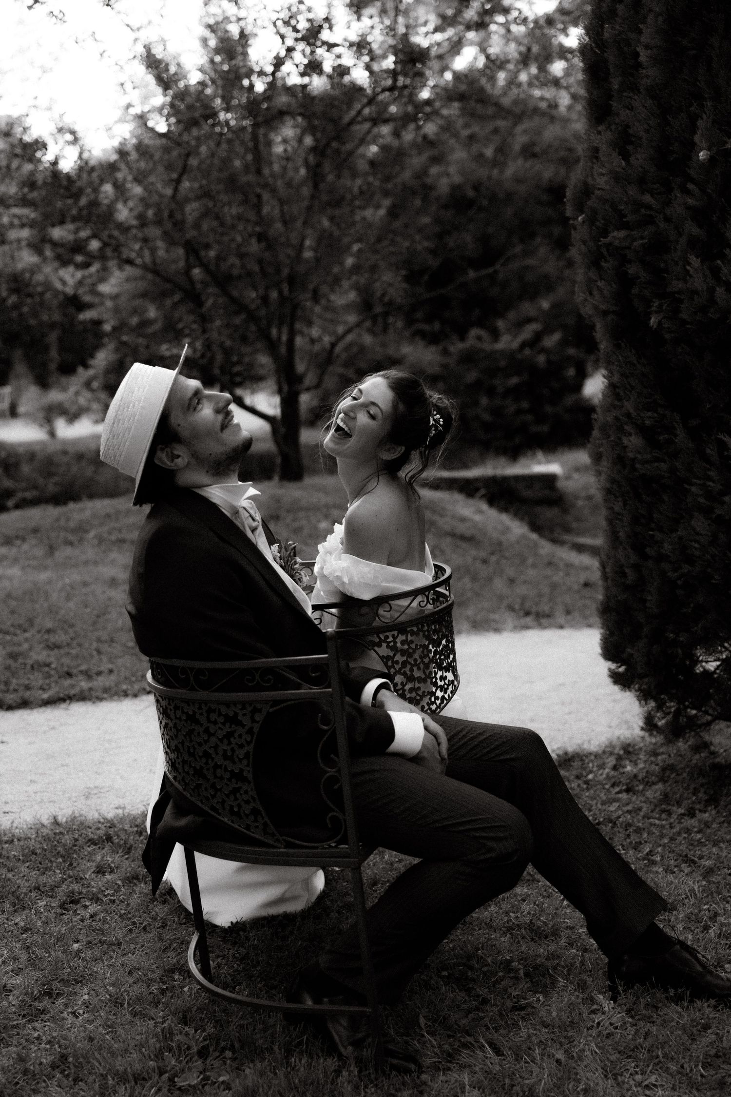 A couple relaxes in a black and white photo sequence while sitting in a chair outdoors.