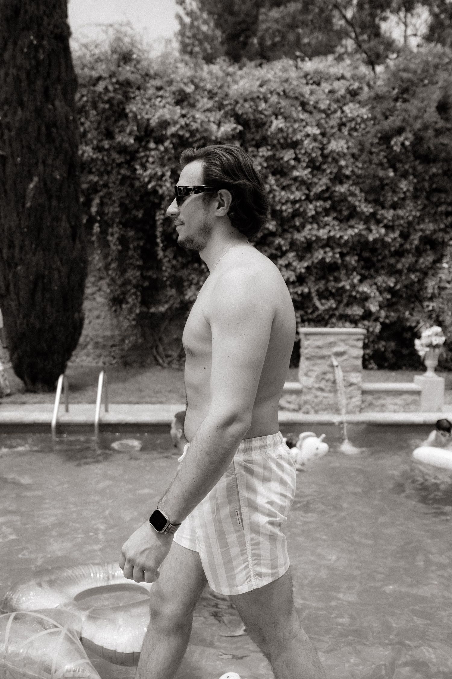 Black and white candid shots of wedding guests by a swimming pool.
