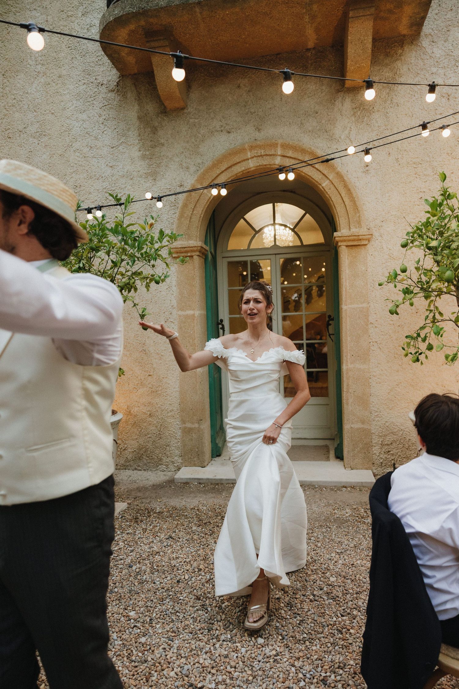 A wedding celebration outside a Mediterranean-style villa with string lights and stone archways.