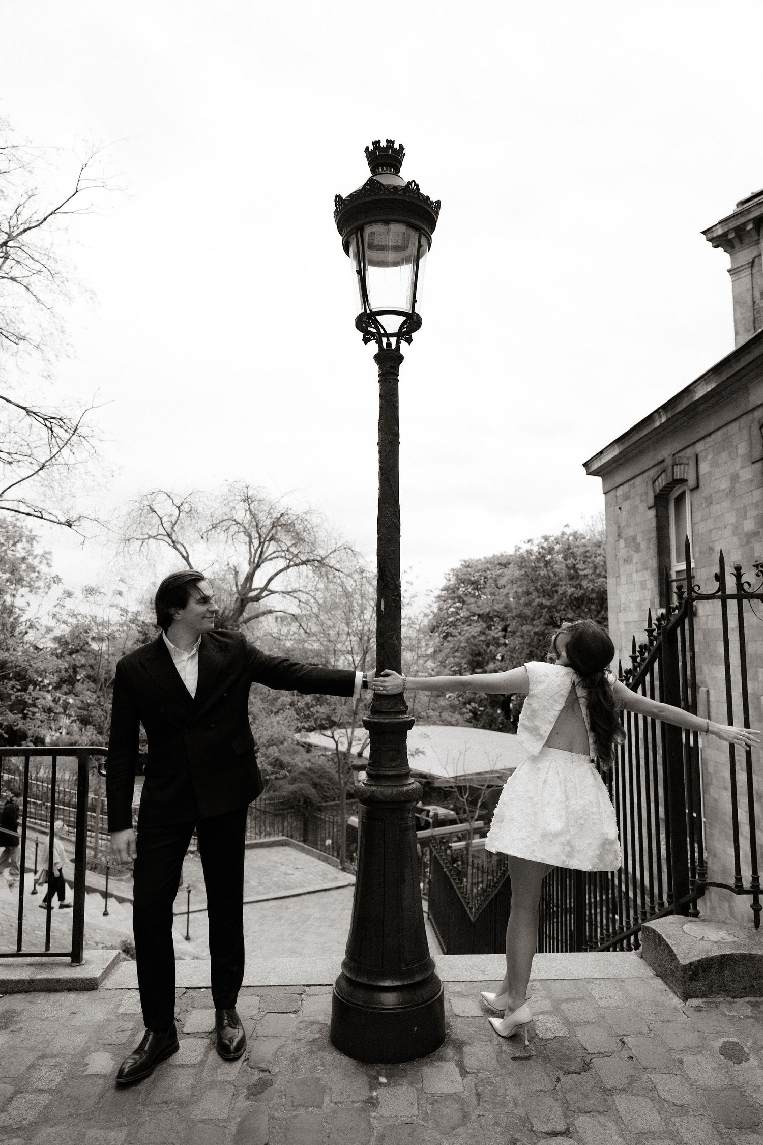 A black and white photo sequence shows a figure dancing with a flowing white cloth on stone steps near a lamp post.