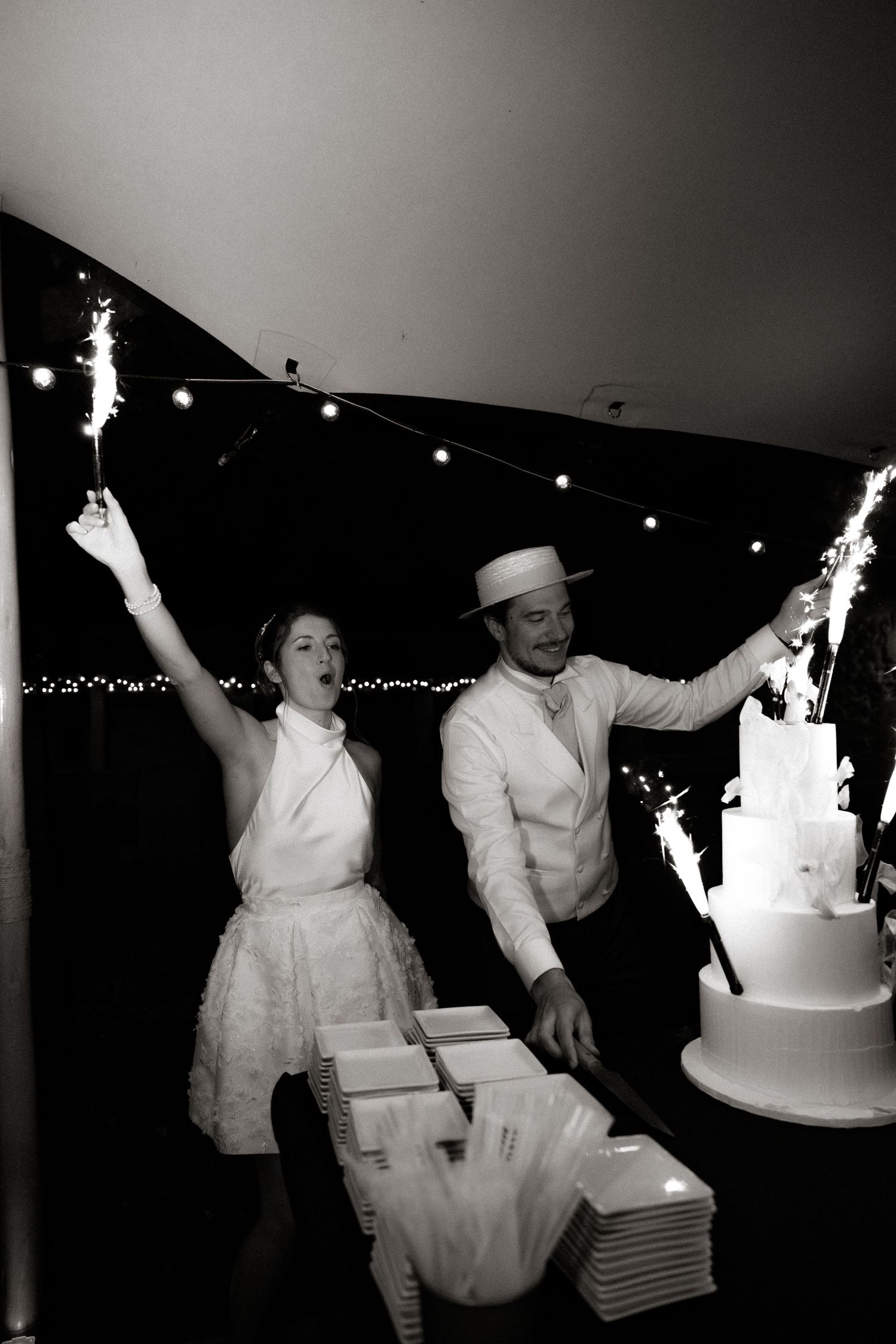 Black and white photos capture sparkler celebration with wedding cake at night.