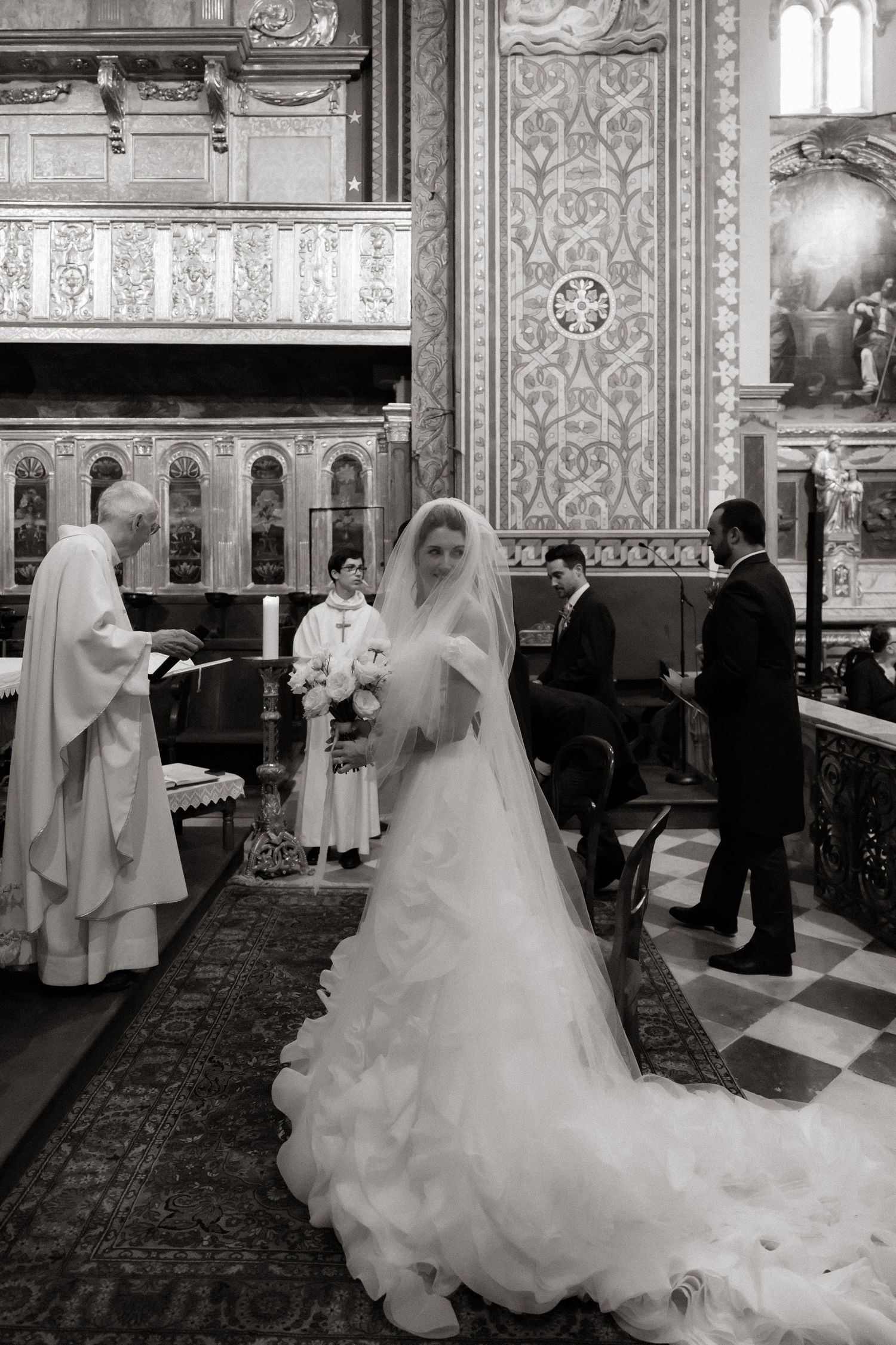 Traditional church wedding ceremony with ornate architectural details captured in black and white.