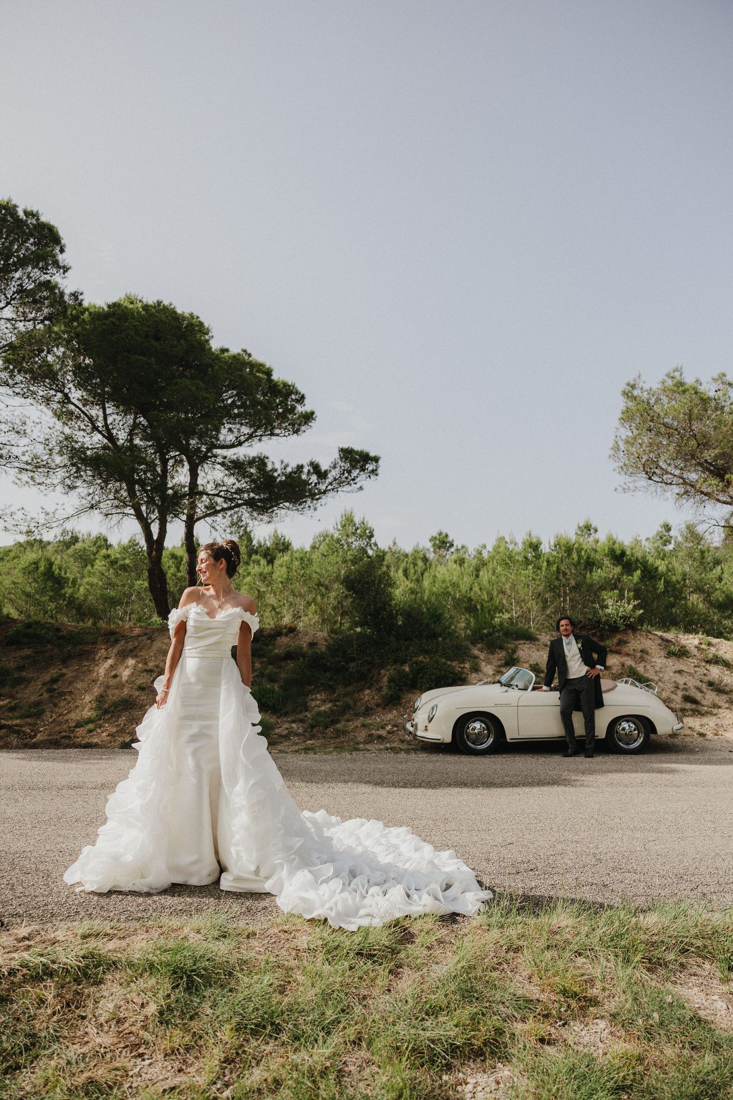 A wedding photoshoot sequence featuring a white wedding dress and vintage car against a scenic hilltop backdrop.