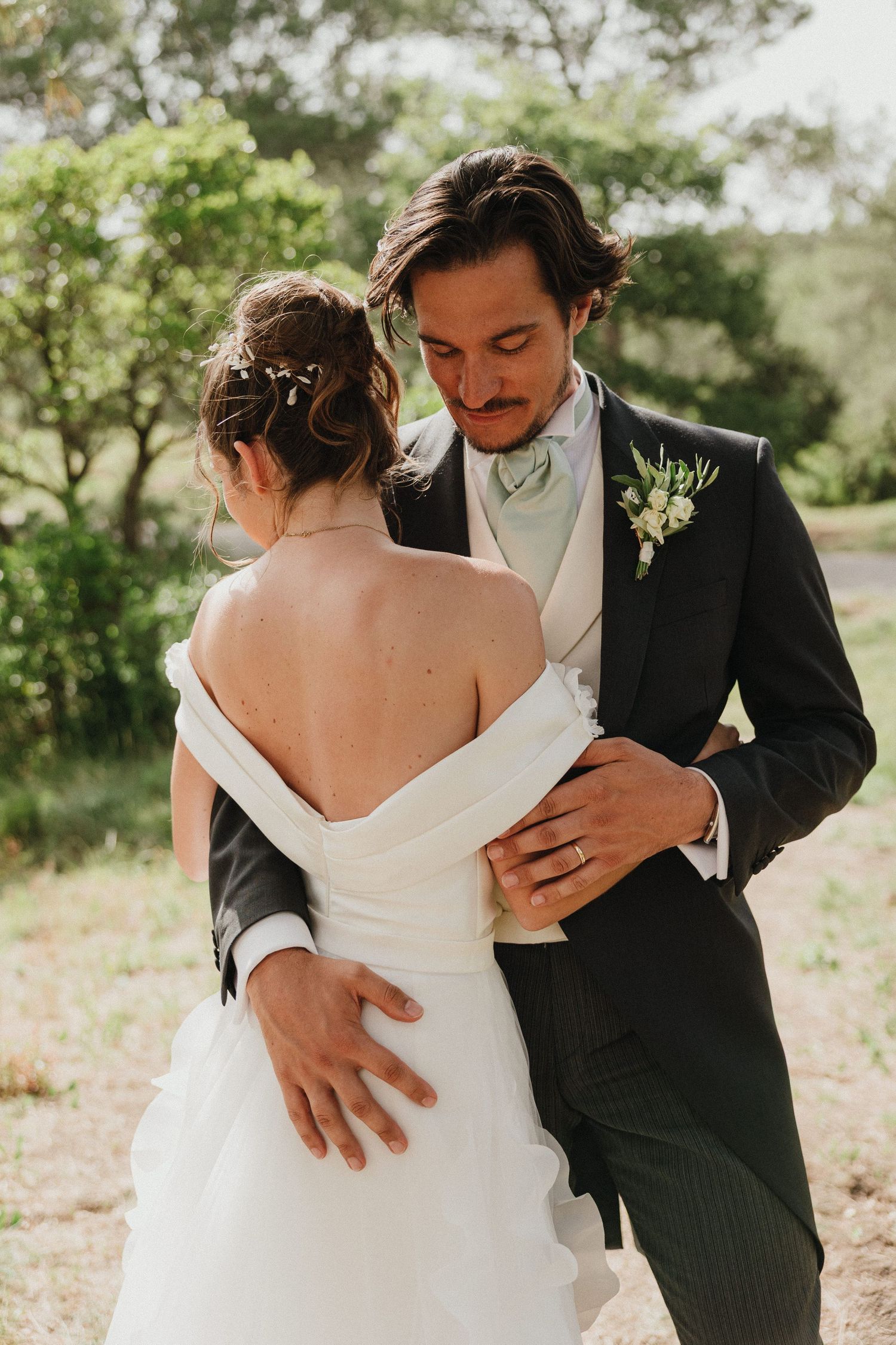 A romantic moment between newlyweds as they embrace outdoors in formal wedding attire.