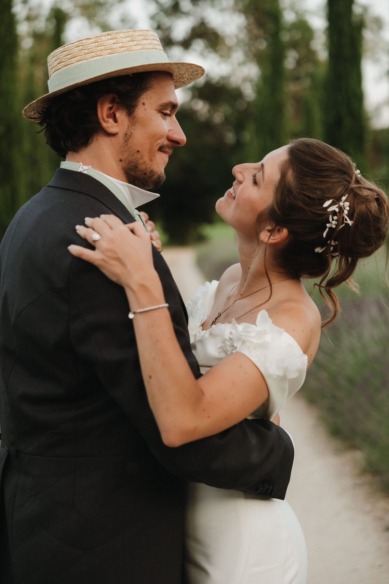 A romantic moment captured between newlyweds with one wearing a straw boater hat.