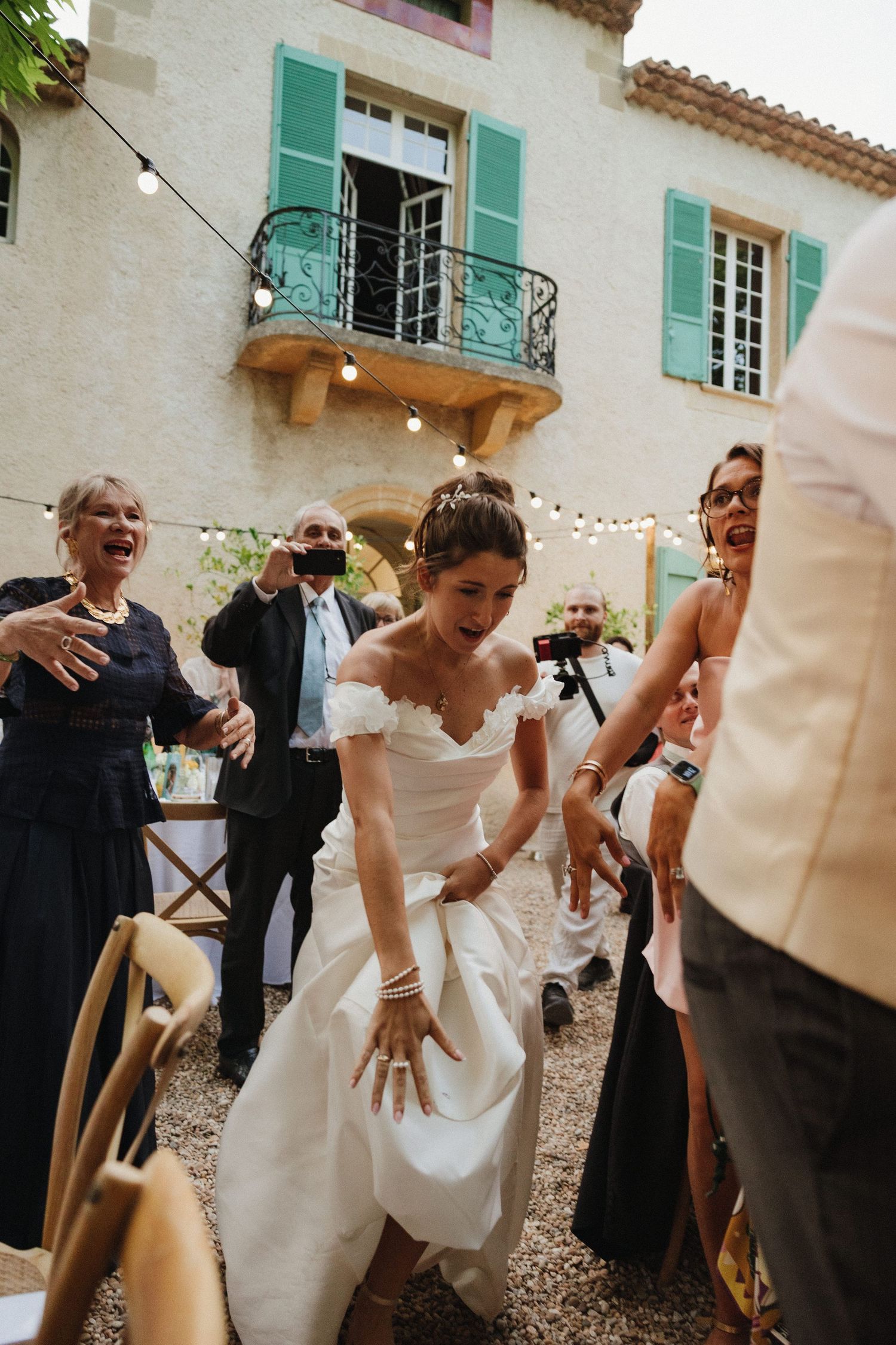 Wedding party members dancing and laughing on a stone patio.