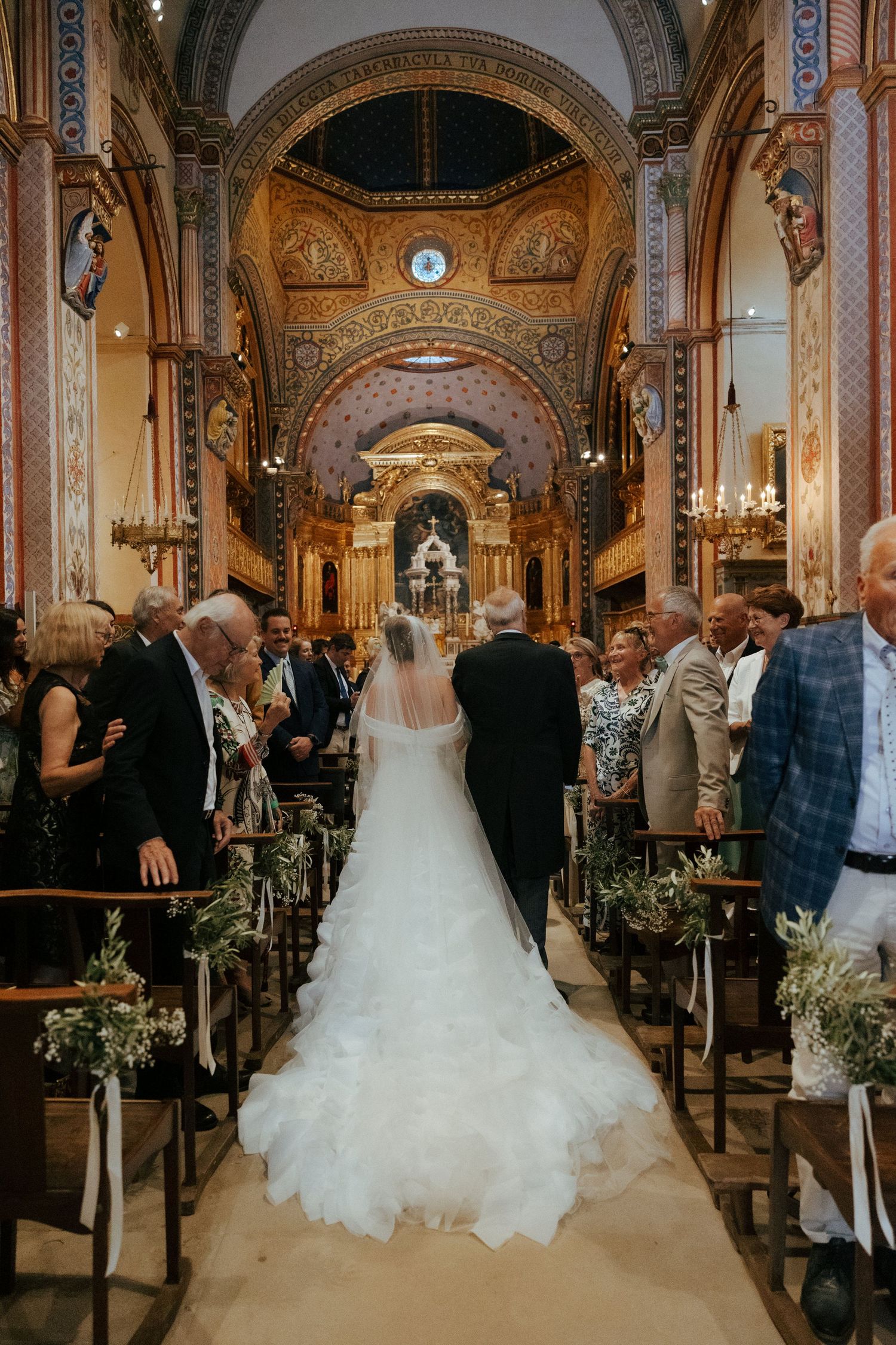 Ornate church interior with decorative arches and columns during a wedding ceremony.
