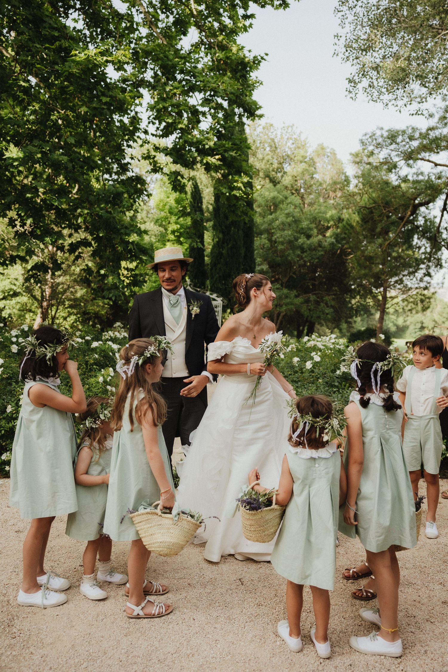 Wedding party in mint green dresses and white sneakers poses casually on garden path.