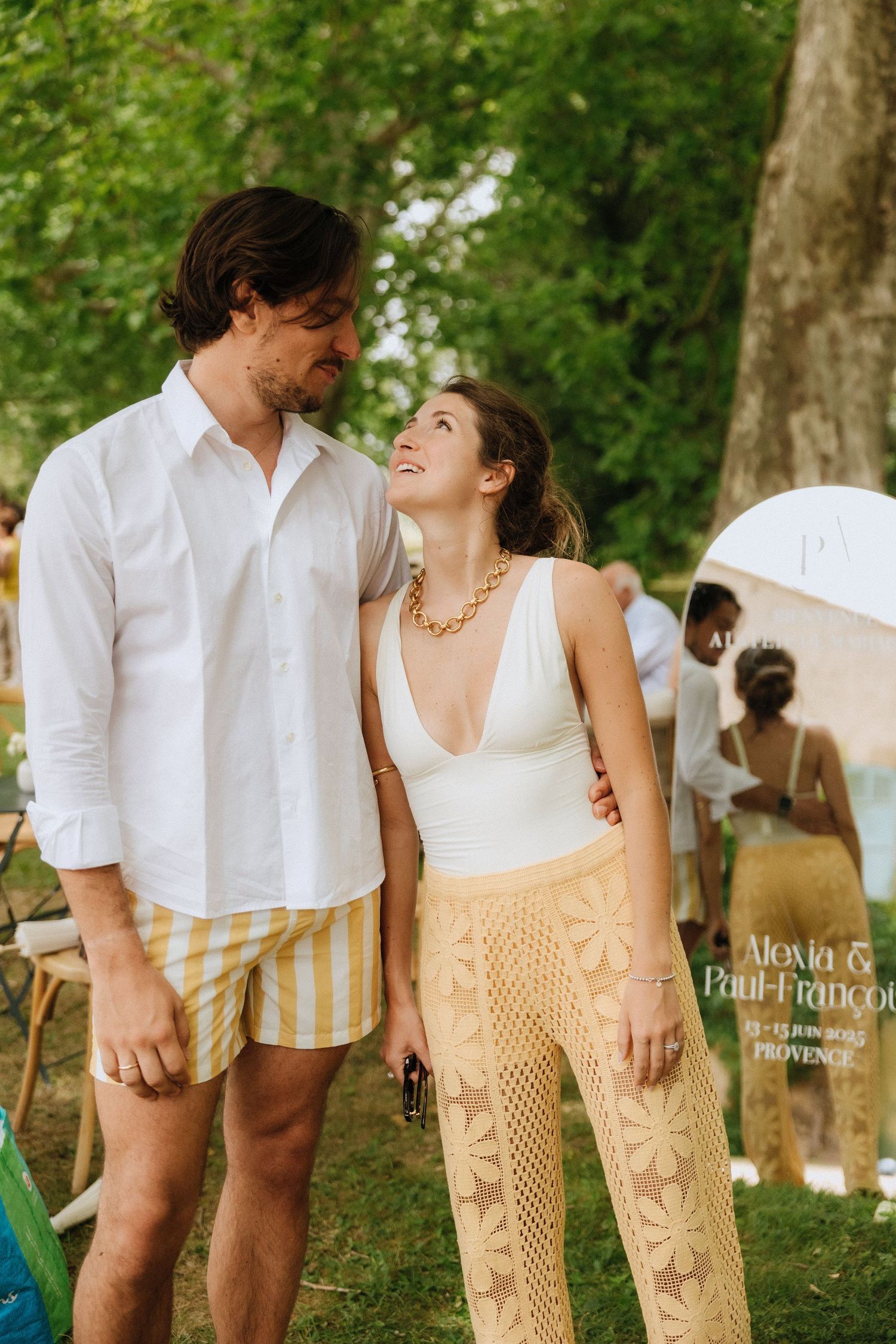 Couple in casual summer wedding attire sharing a playful moment outdoors.