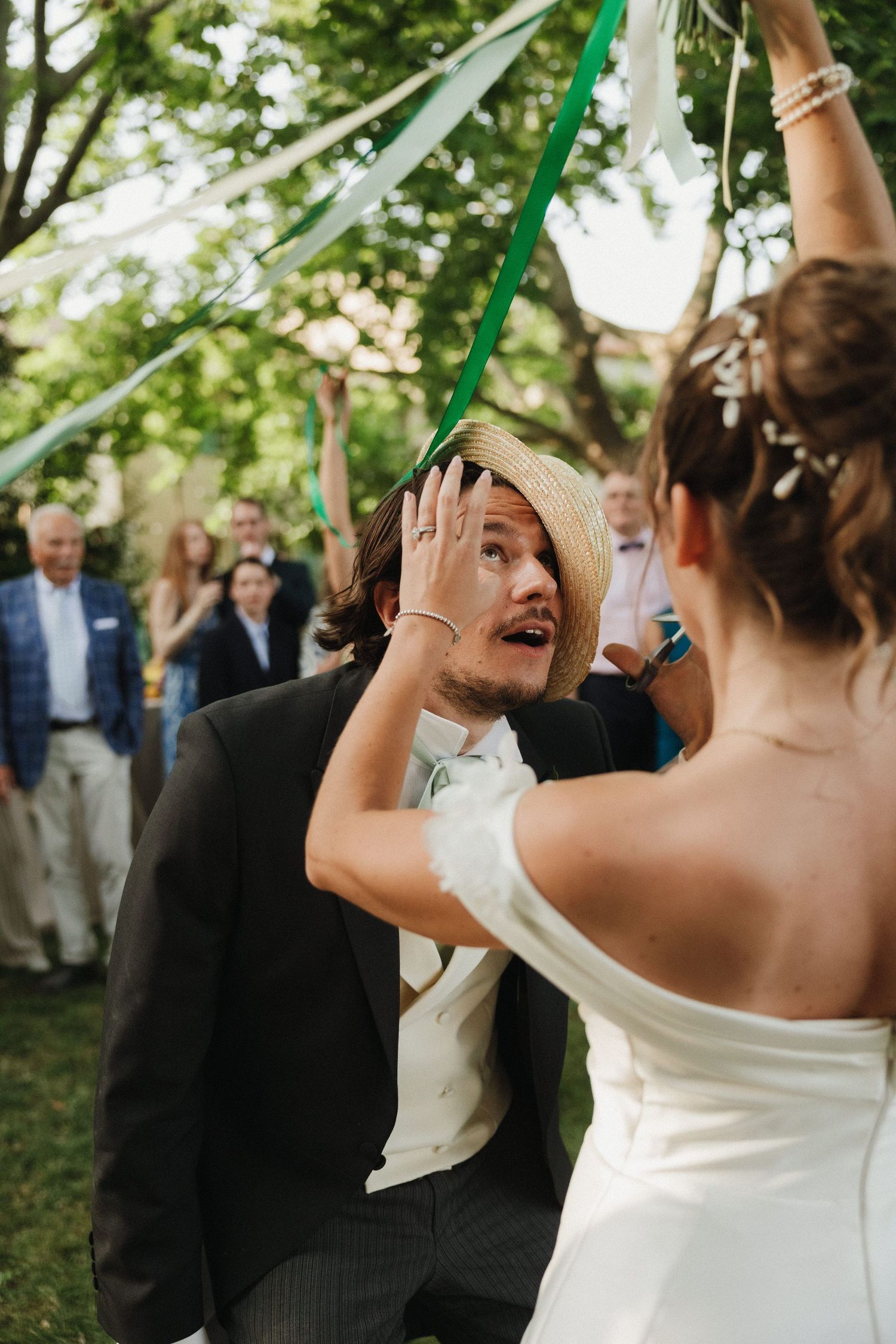 Wedding celebration outdoors with guests dancing and green streamers flying through the air.