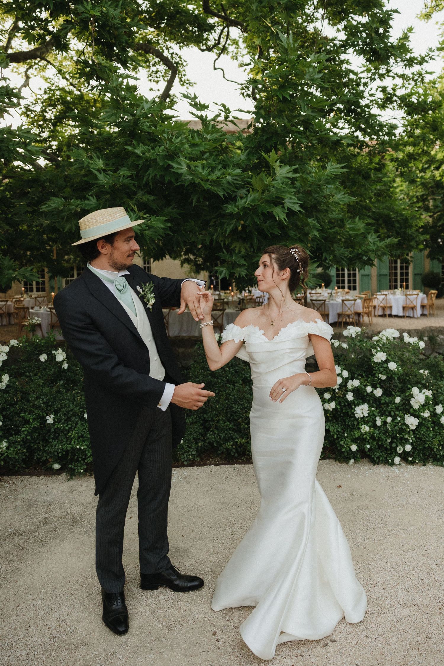 Wedding couple dancing together in a garden setting with white flowers.