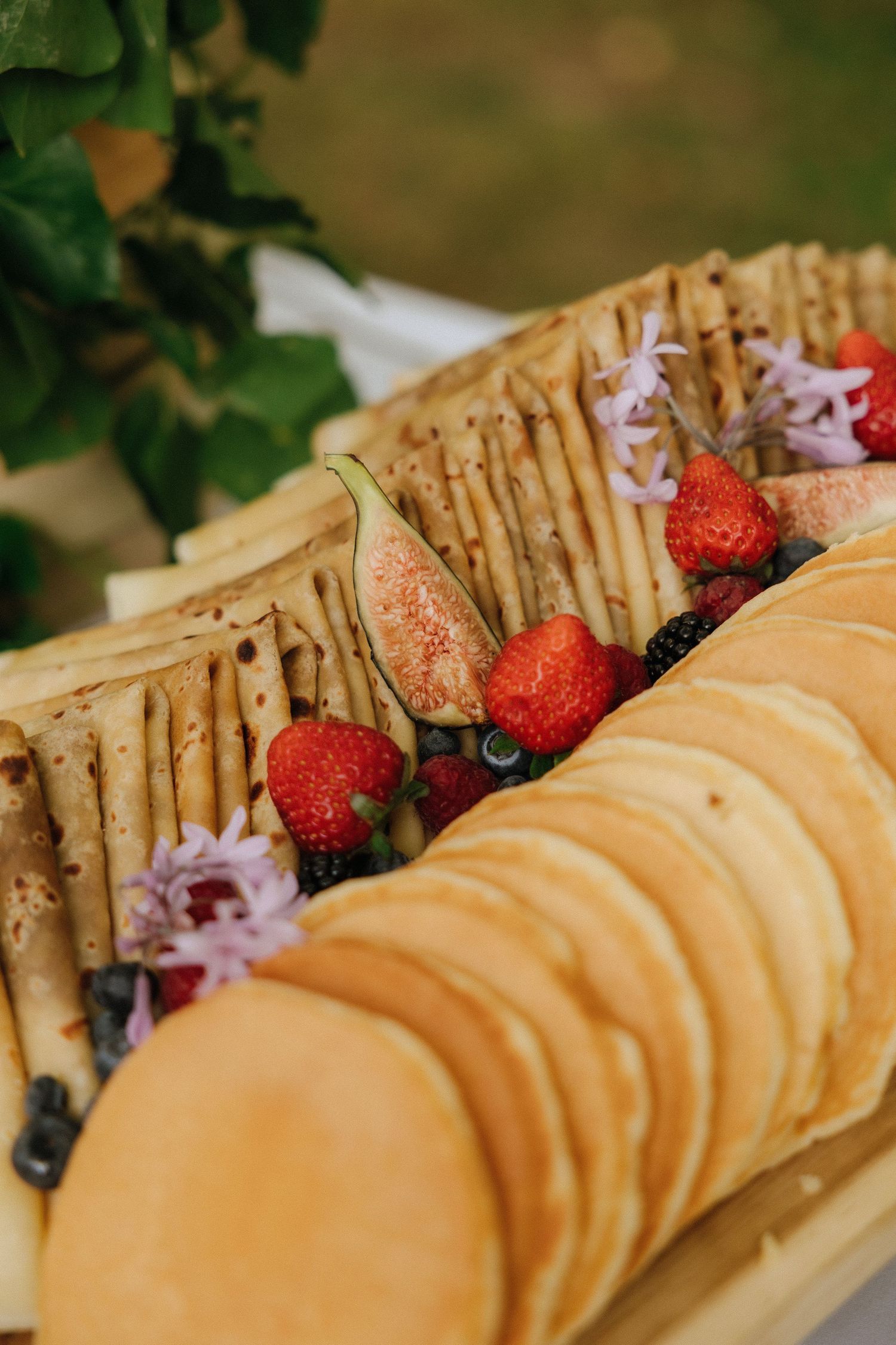Artfully arranged pancakes with fresh strawberries on a rustic wooden platter.