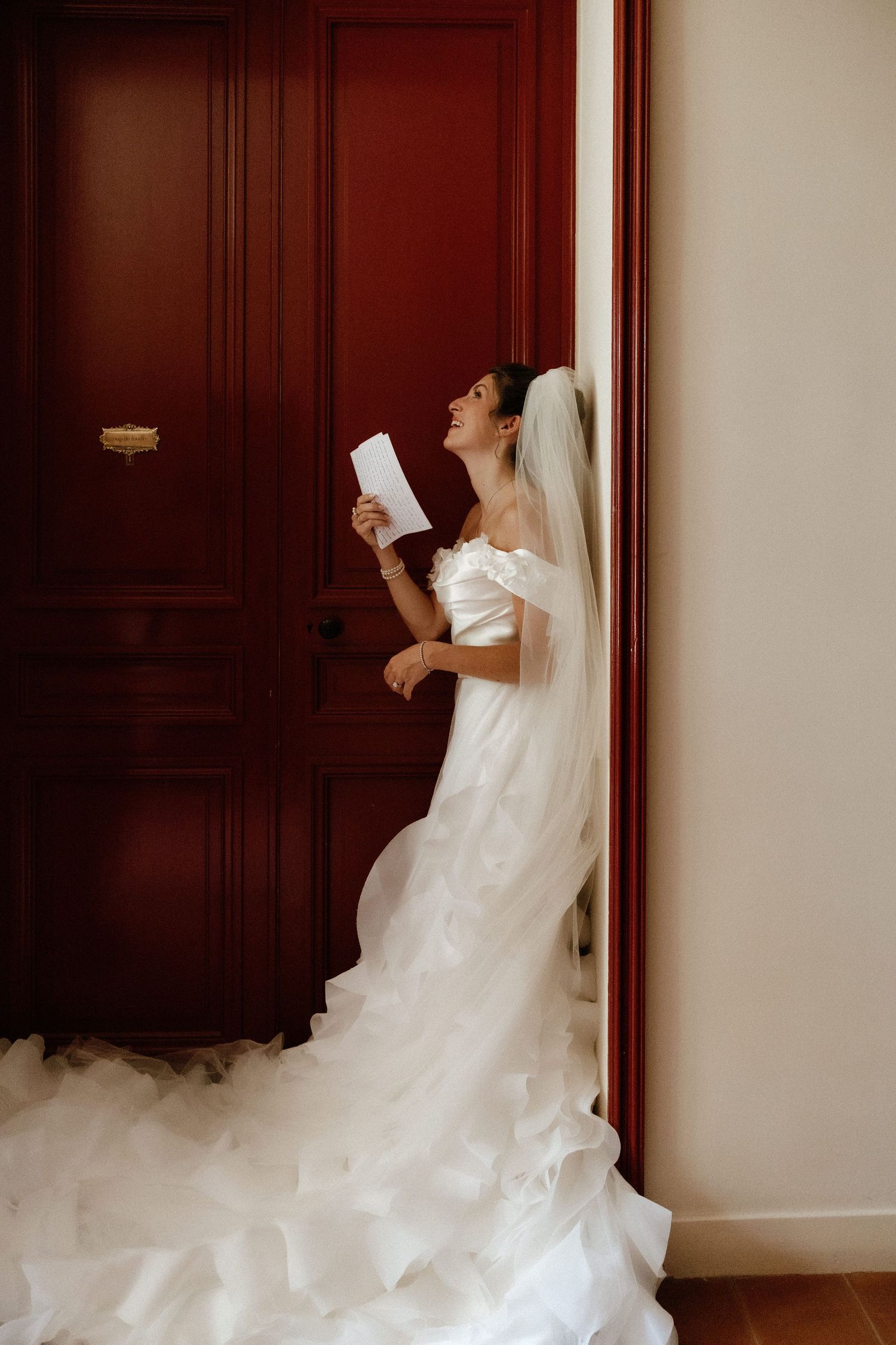 Dramatic bridal portrait series showing flowing white wedding gown against burgundy walls.