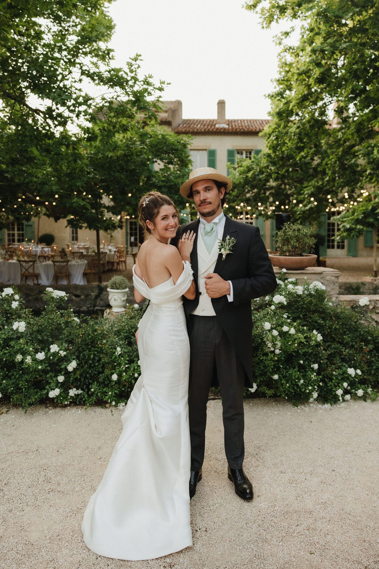 Newlyweds dancing and celebrating in a garden setting with white flowers.