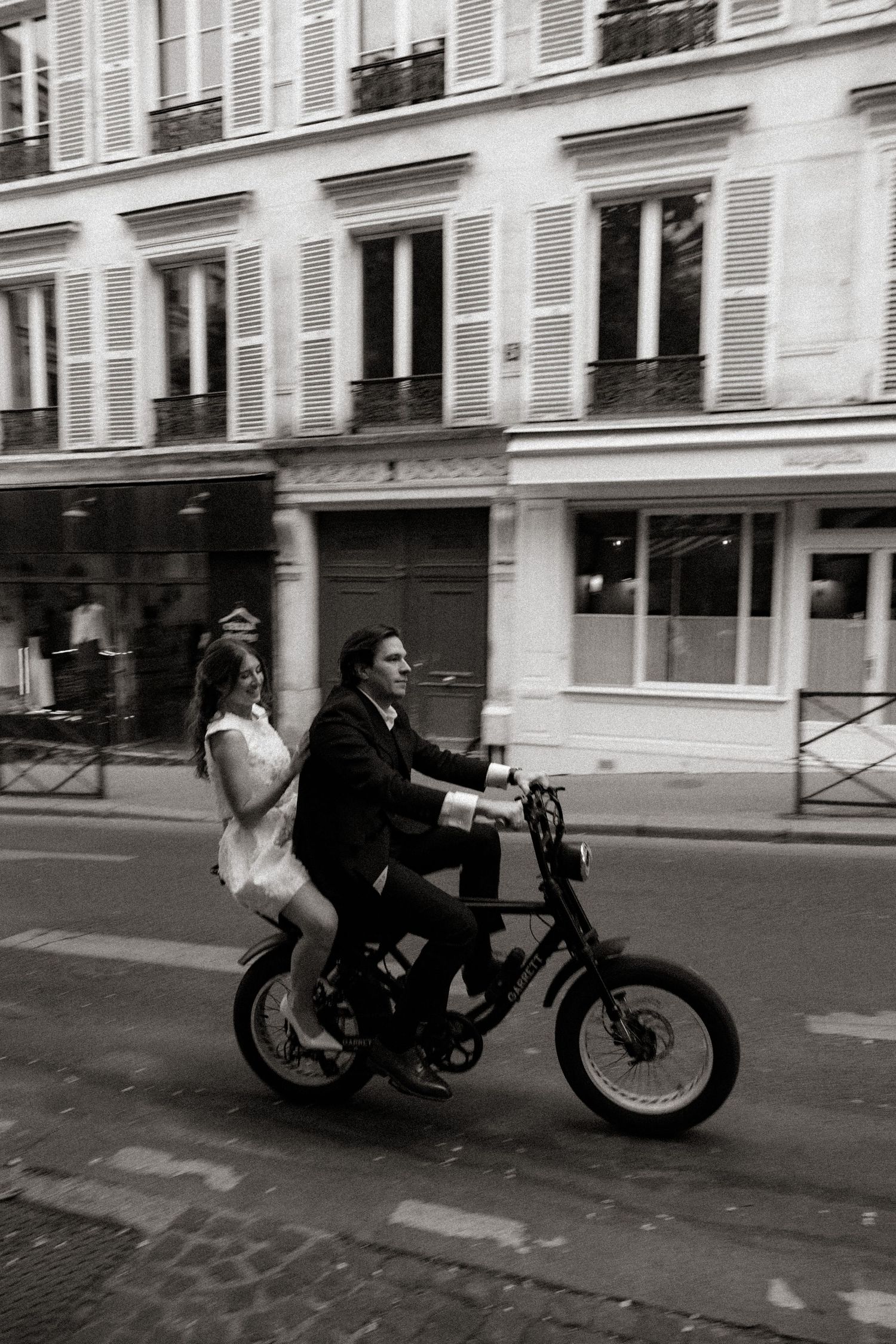 A sequence of black and white photos showing a motorcycle rider speeding down a Parisian street.