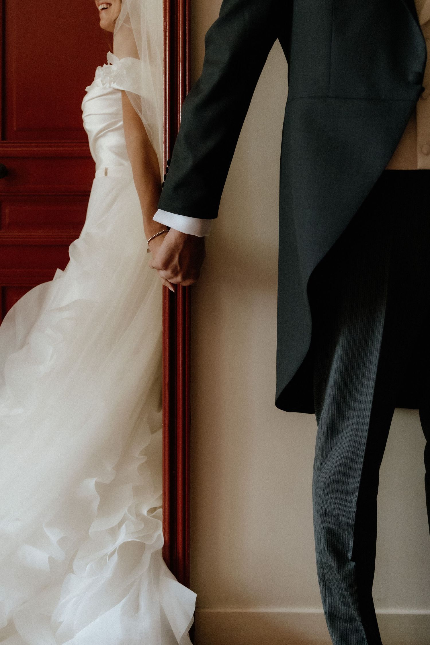 Close-up details of a flowing white wedding dress and black formal suit.