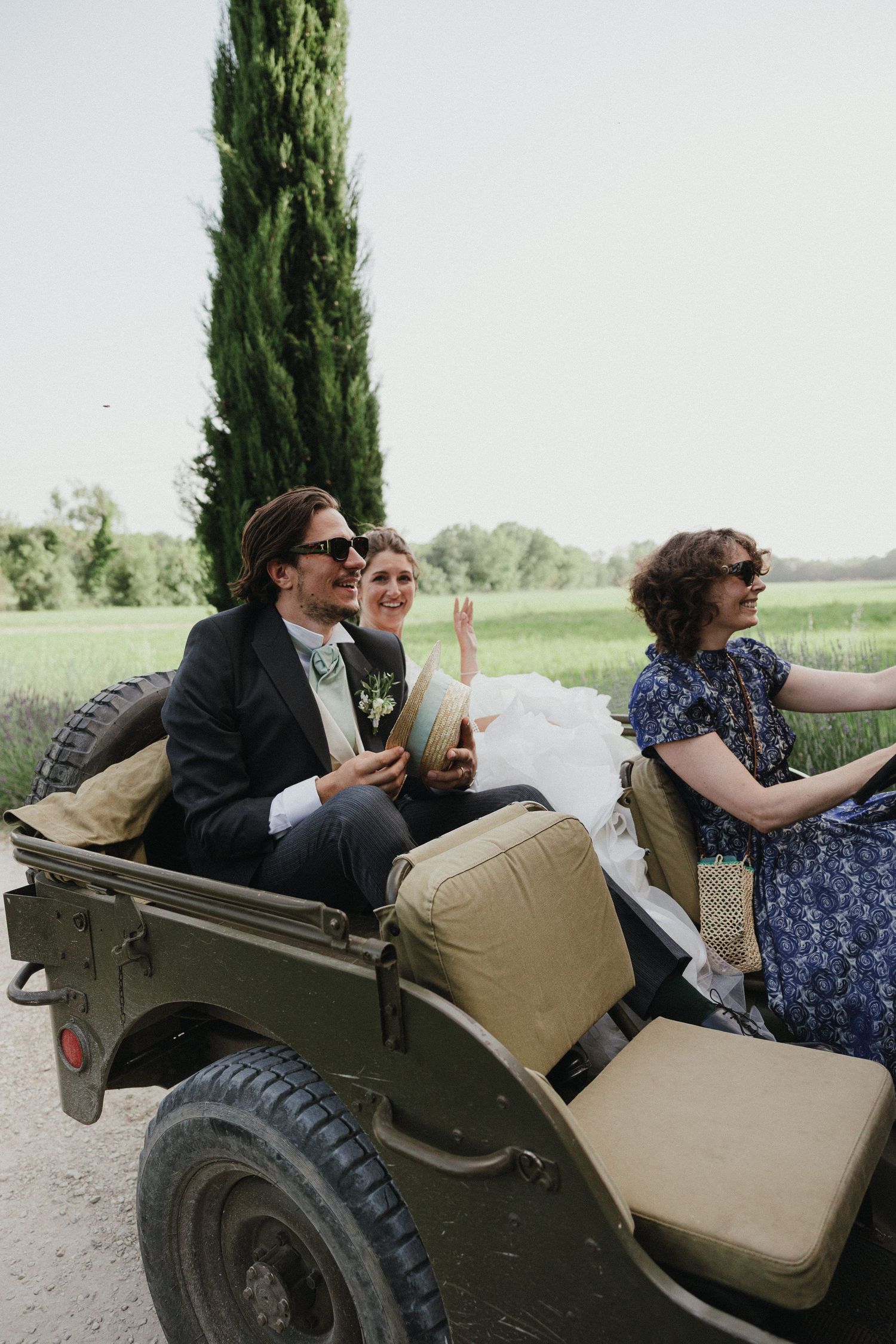Wedding party rides in vintage military vehicle during outdoor celebration.