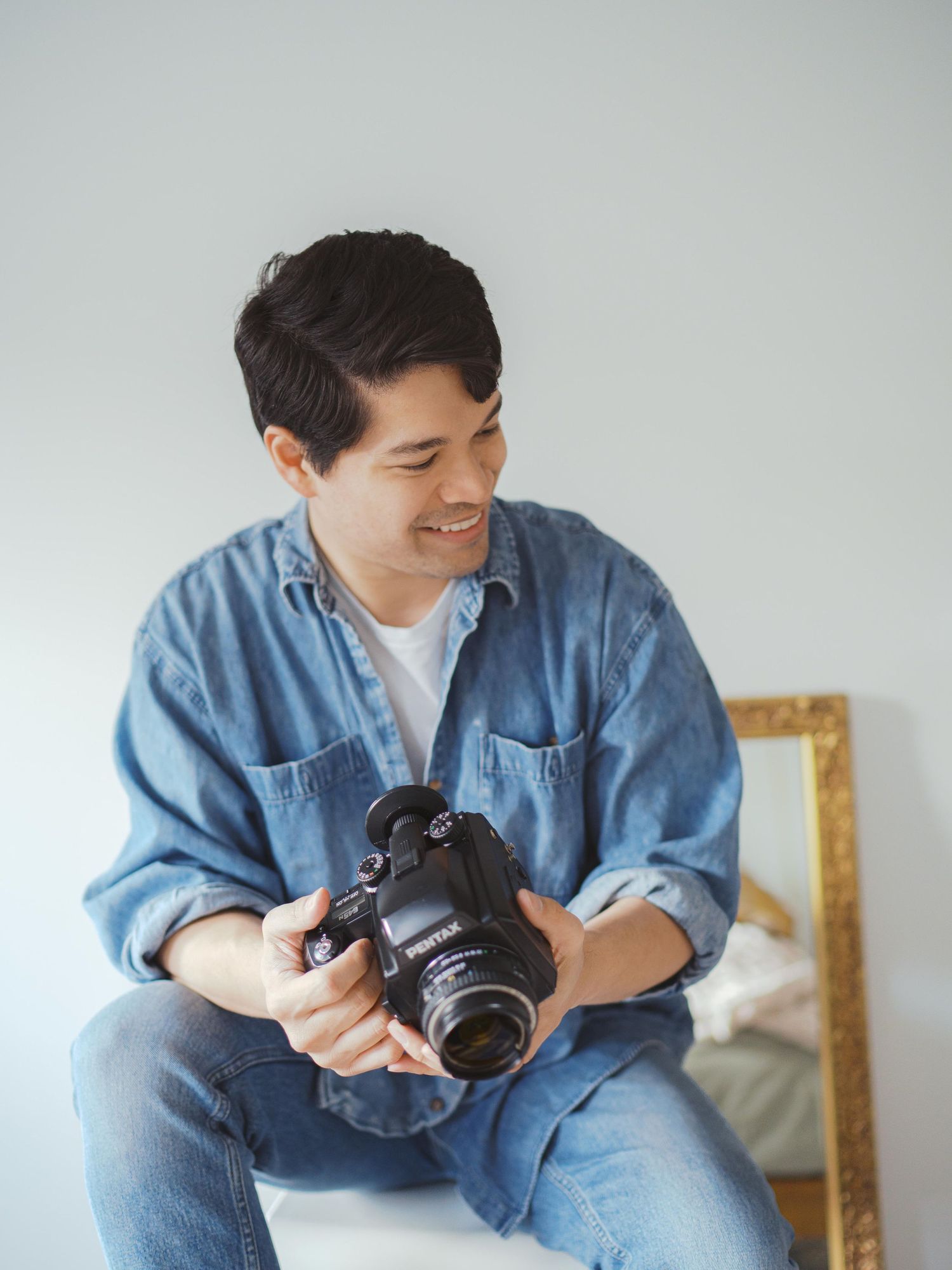 Seattle family photographer smiling in a denim shirt while reviewing images on a film camera capturing the artistry behind family photos