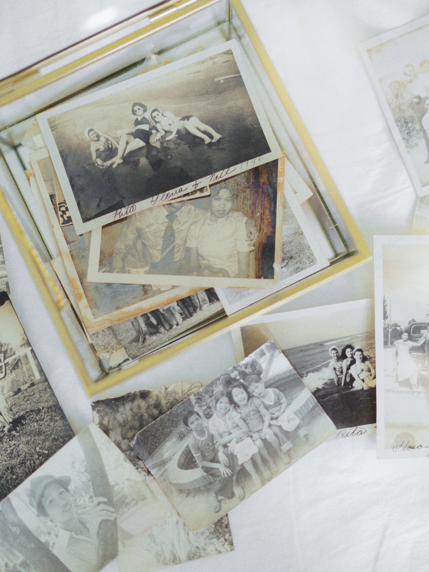 A collection of vintage black and white photographs scattered on a white surface showing nostalgic moments from the past.