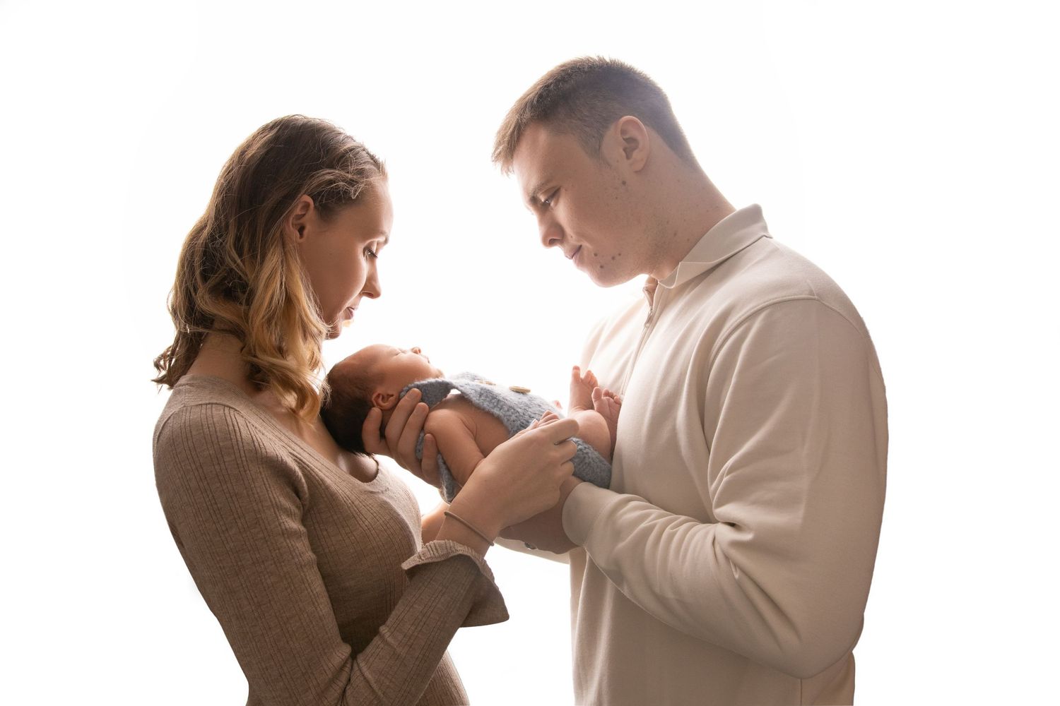Parents holding newborn baby during intimate family portrait session.