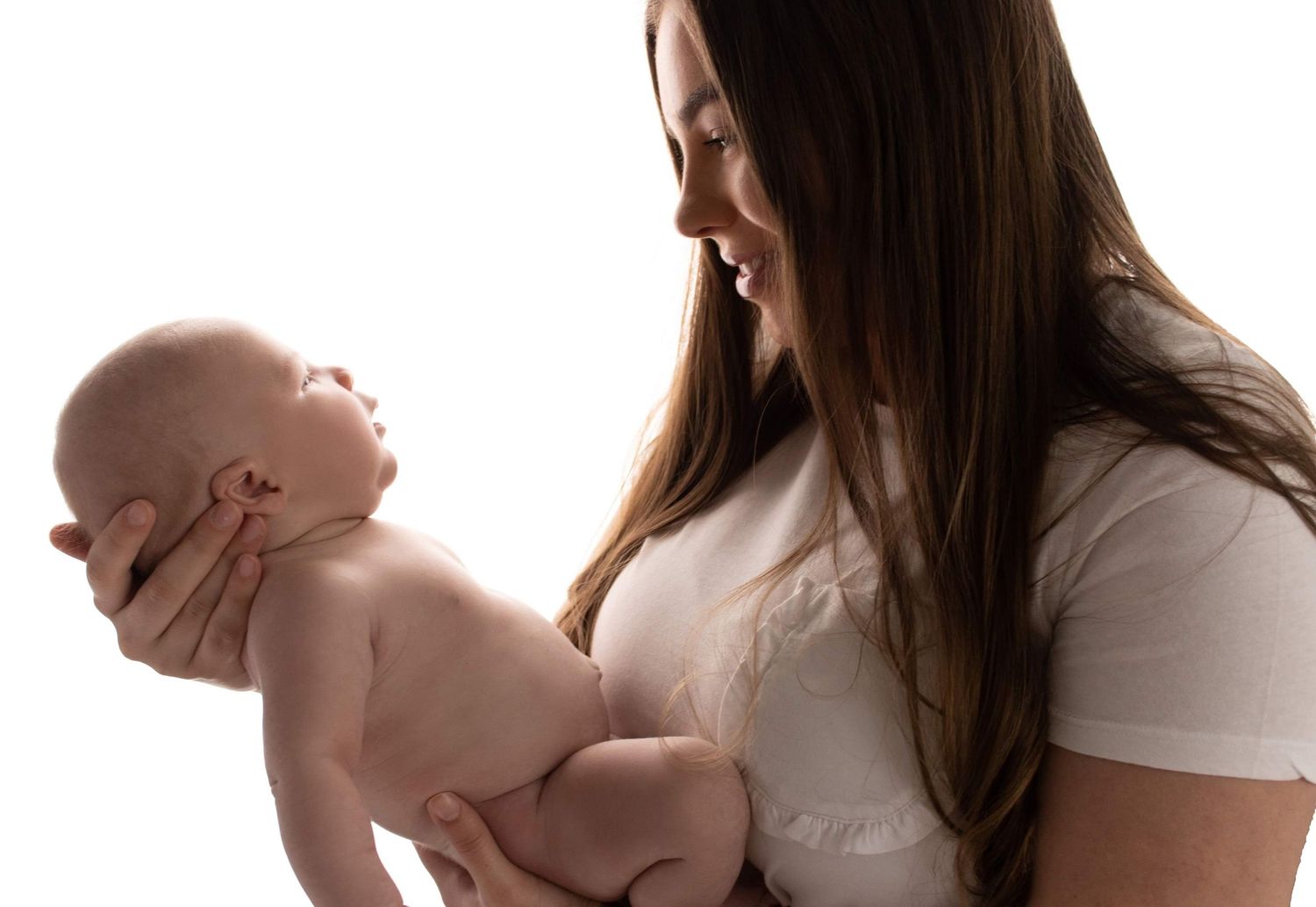 Mother holding newborn baby during backlit studio photography session.