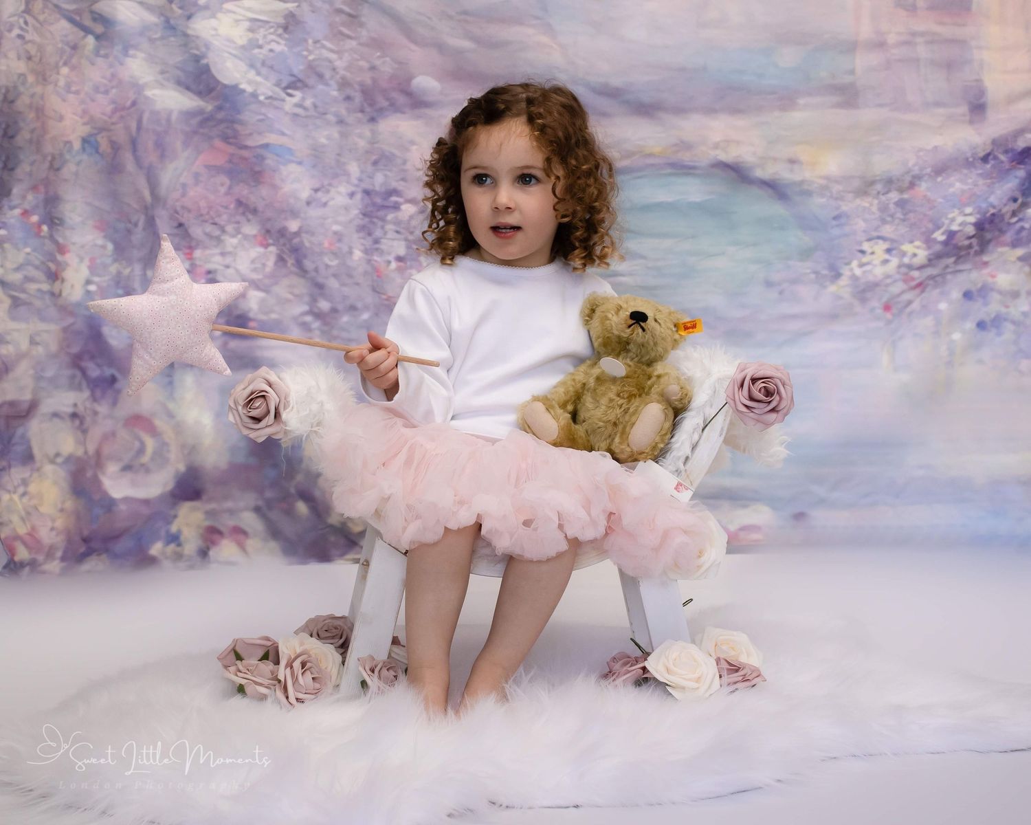 A dreamy studio portrait featuring a pink tutu and teddy bear against a purple ethereal backdrop.