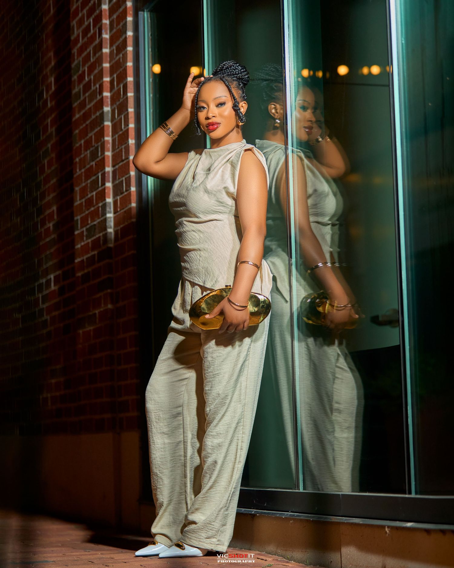 Fashion portrait against brick wall and glass windows in evening light.