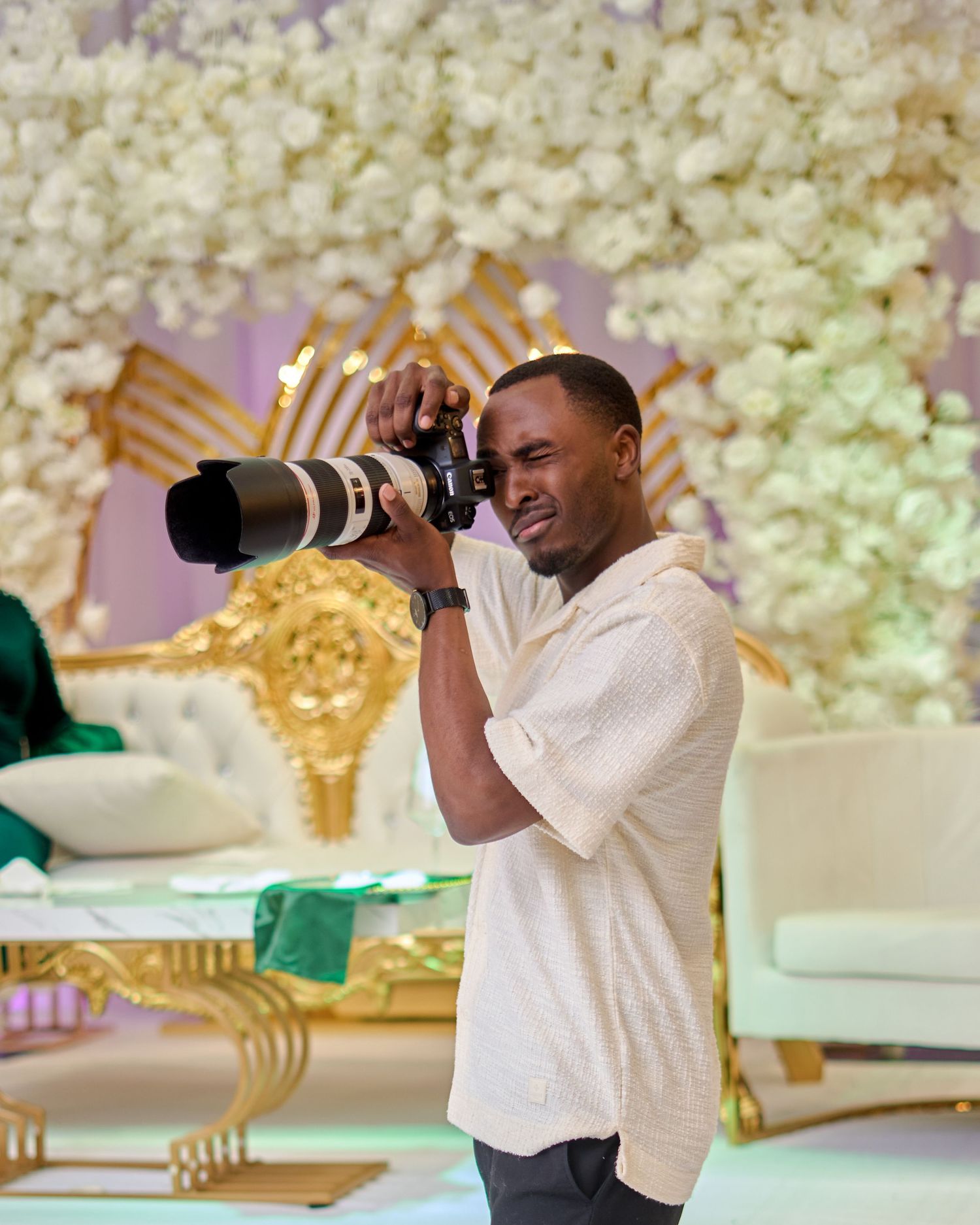 Professional photographer in white shirt capturing moments at an elegant event with floral decor.