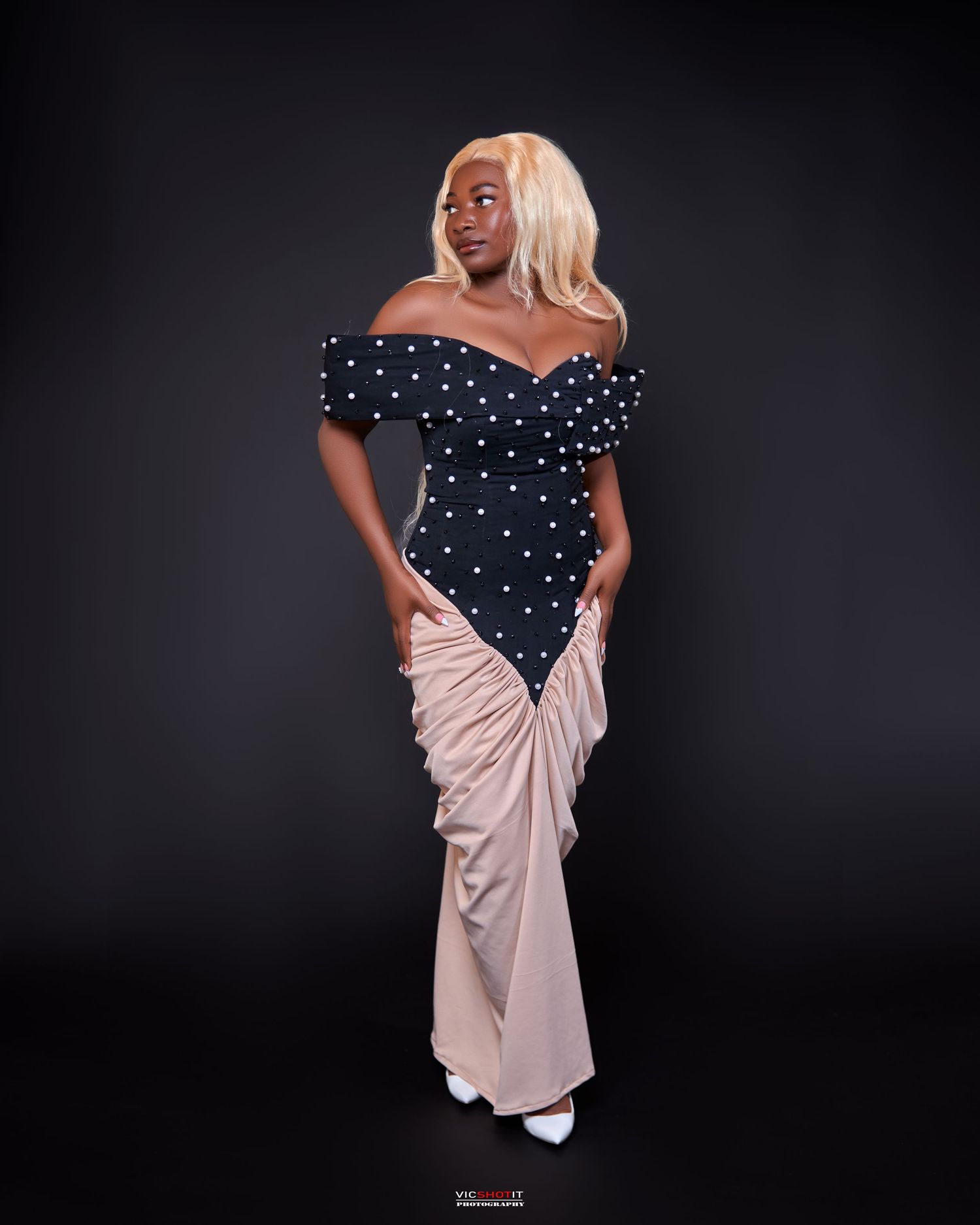Elegant contrast of navy polka dot dress and beige wrap in dramatic studio portraits.