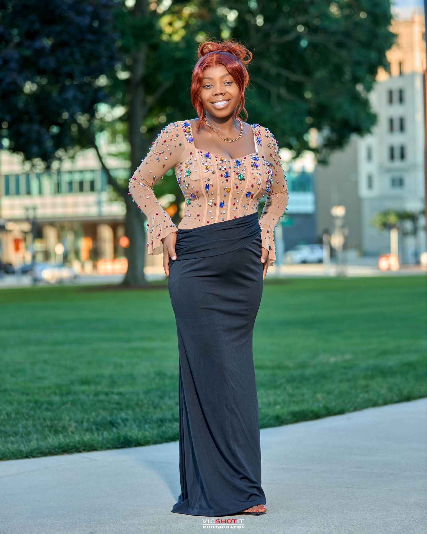 Summer evening portrait session on a path with buildings and green lawn in background.