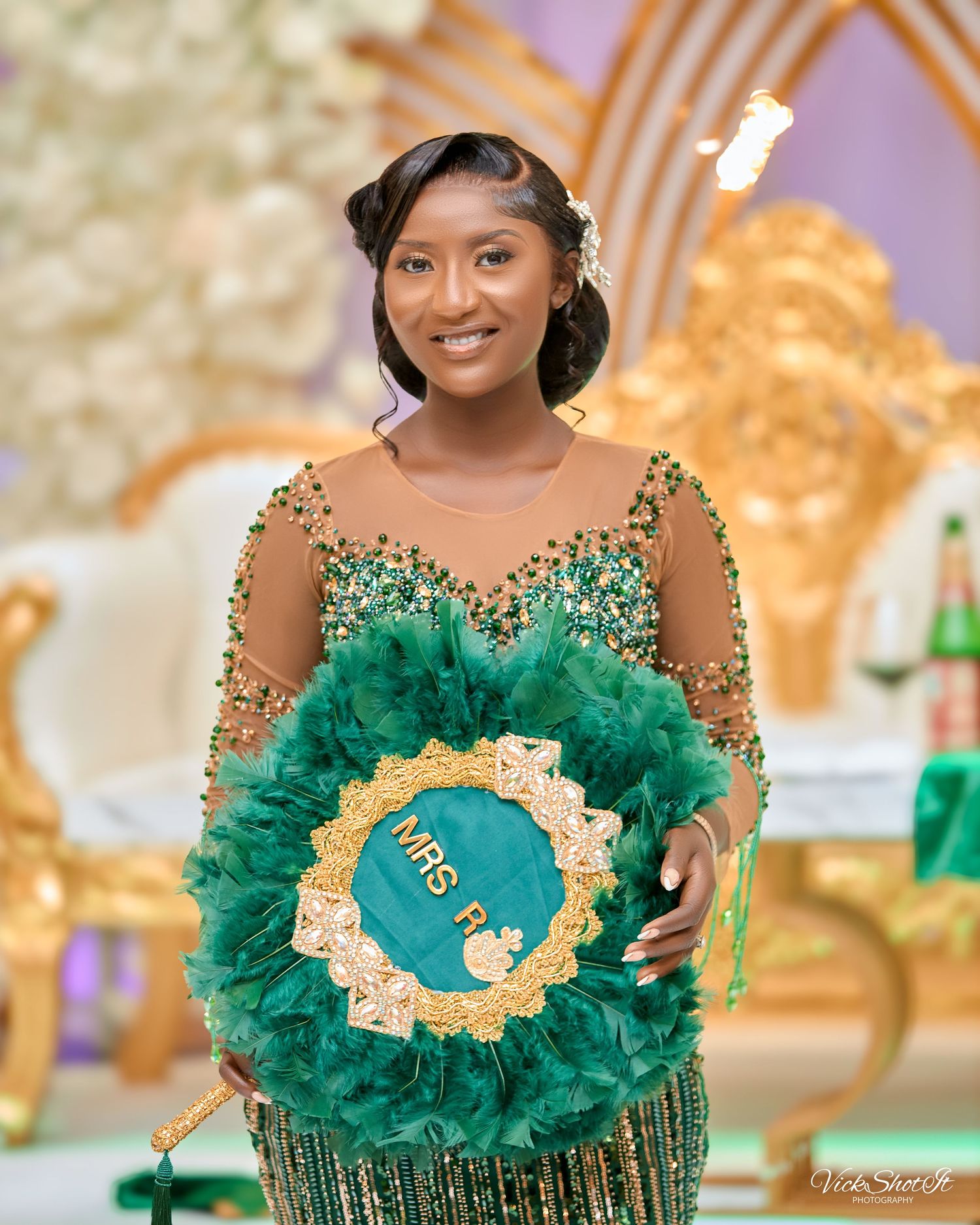 An elegant wedding reception featuring a person in a sparkling green gown holding a decorative wreath.