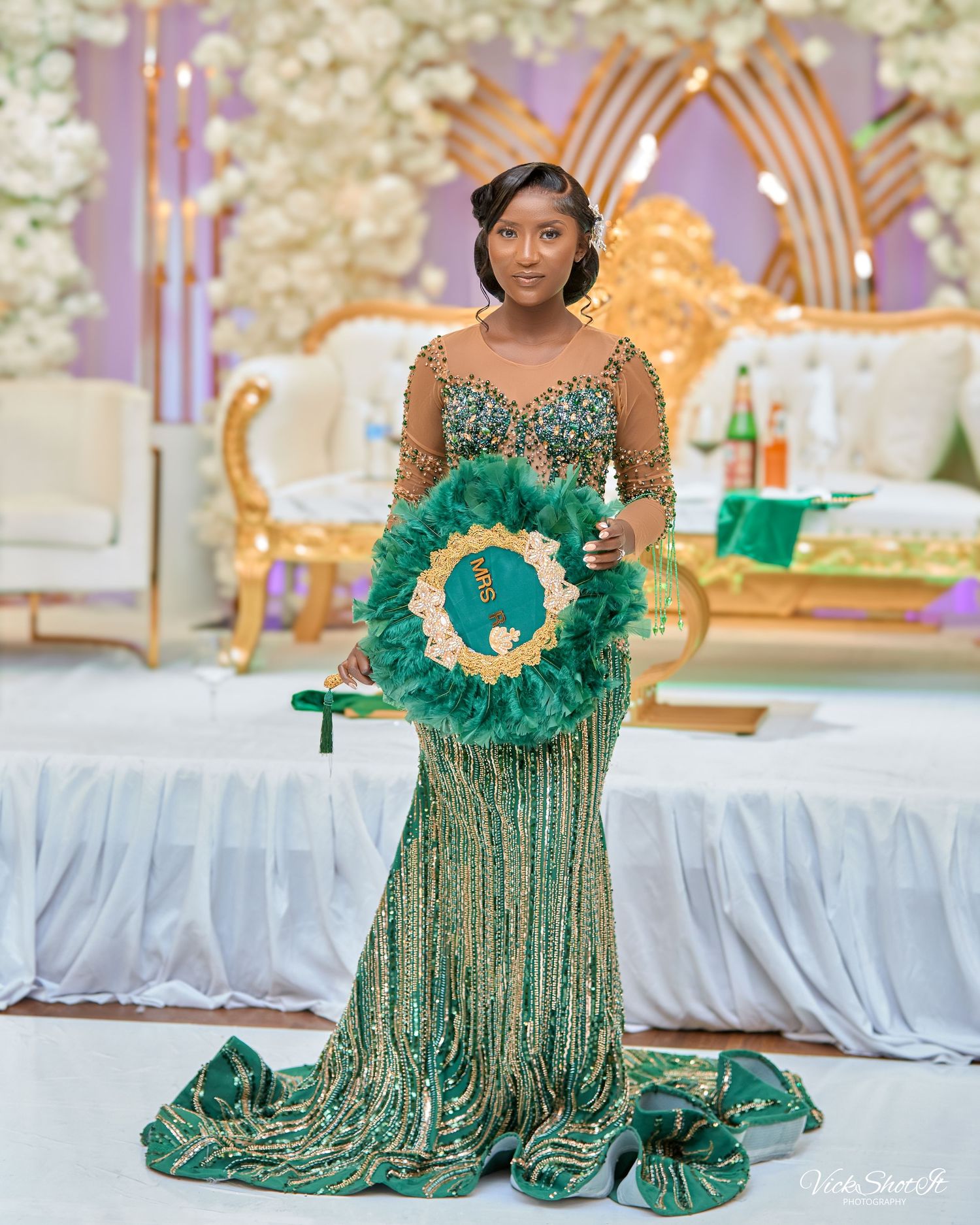 A wedding reception scene with elegant decor featuring a sparkling green gown and decorative wreath.