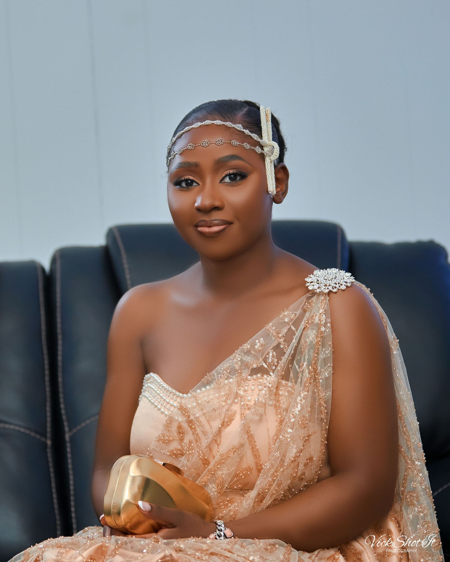 A woman in a shimmering peach gown with crystal details reclines on a sofa.