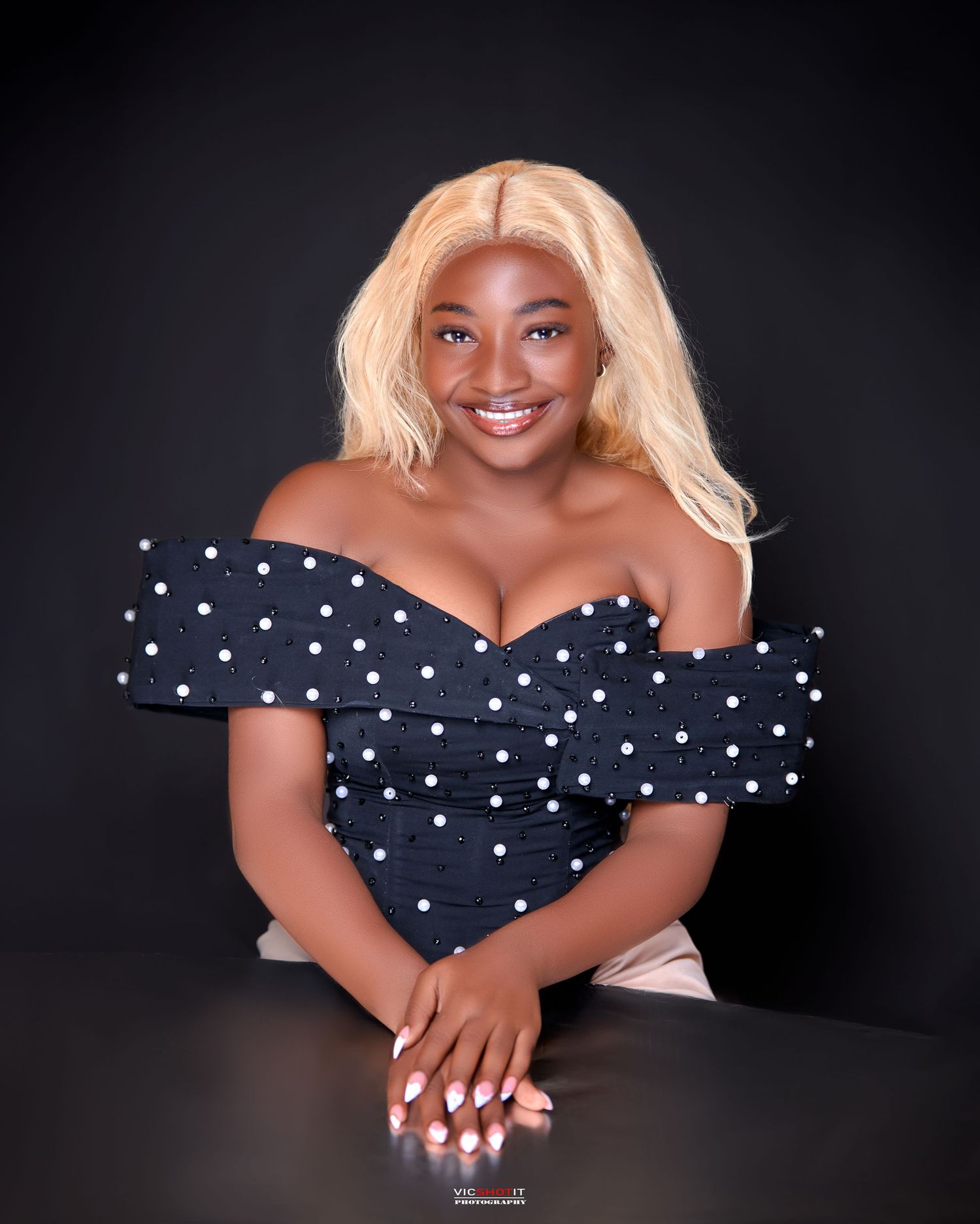 Studio portrait in black and white polka dot dress with blonde hair.