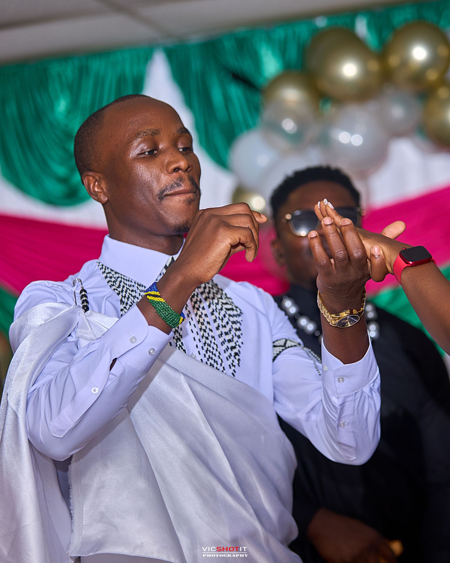 Wedding guest in white shirt wiping tears during emotional ceremony moment.