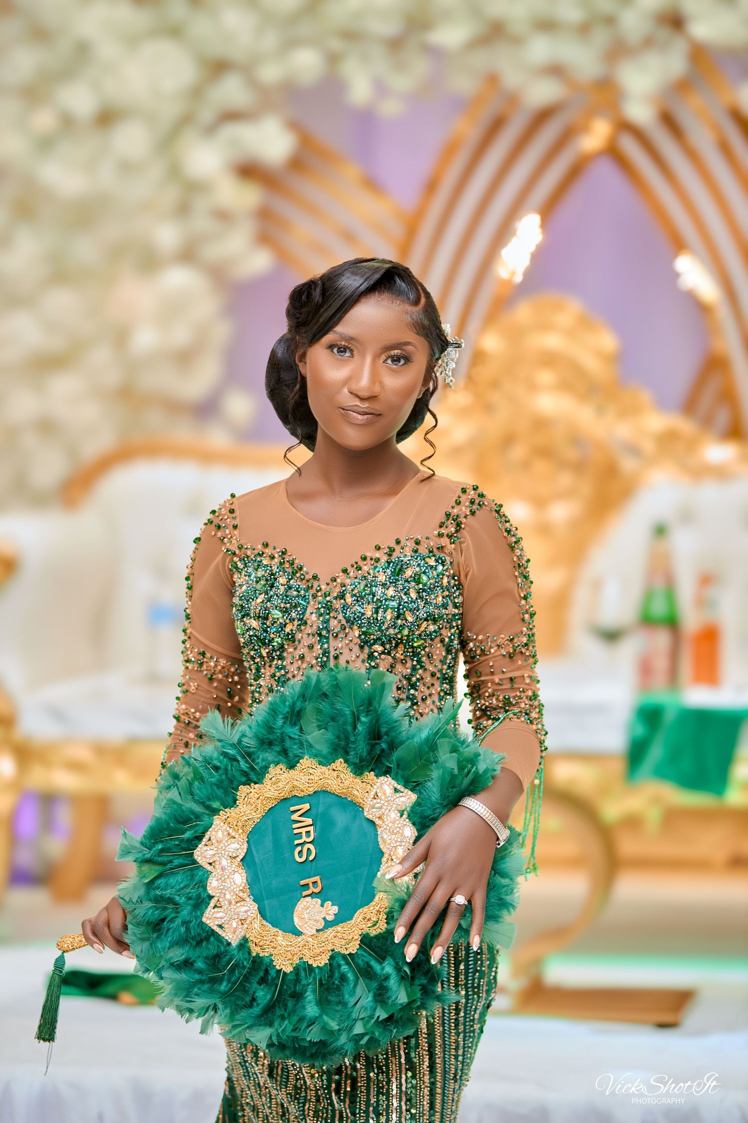 An elegant emerald green beaded gown with sheer details is showcased at a formal event.