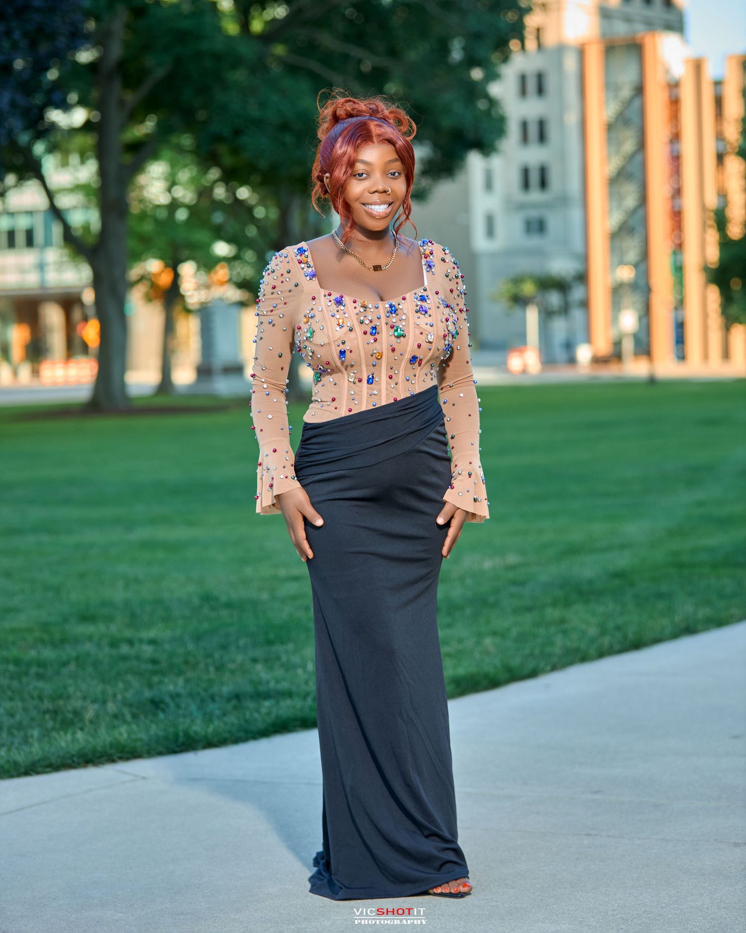 Outdoor photoshoot featuring a black dress with floral overlay against a grassy backdrop.