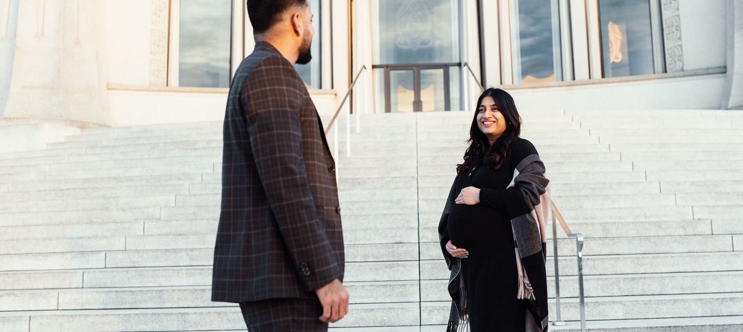 A couple standing on stone steps in front of a building having a conversation.