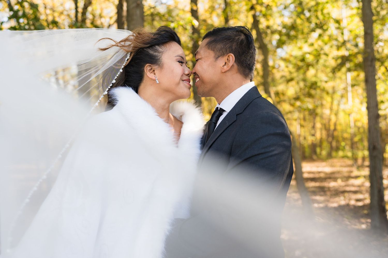 A romantic moment captured through a flowing white veil in an autumn setting.