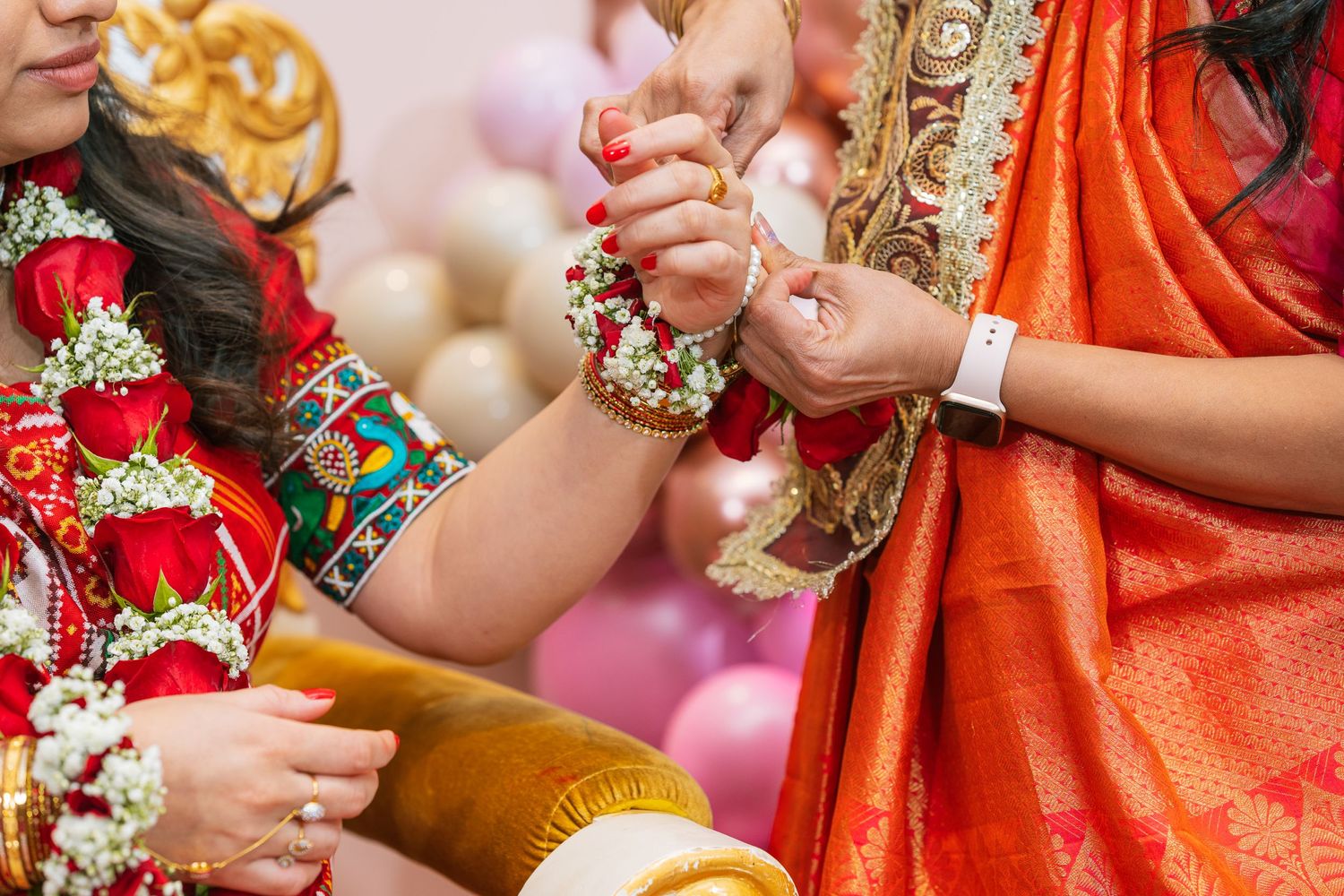 Close-up of hands wearing traditional Indian bangles and jewelry during a ceremonial ritual.