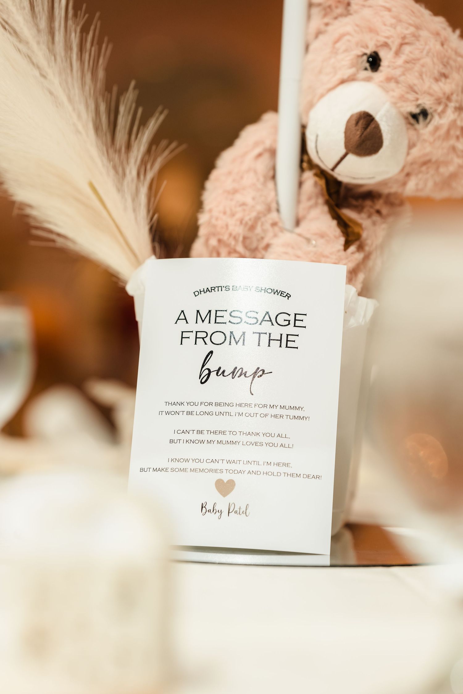 A message card with feather decoration and teddy bear at a baby shower celebration.
