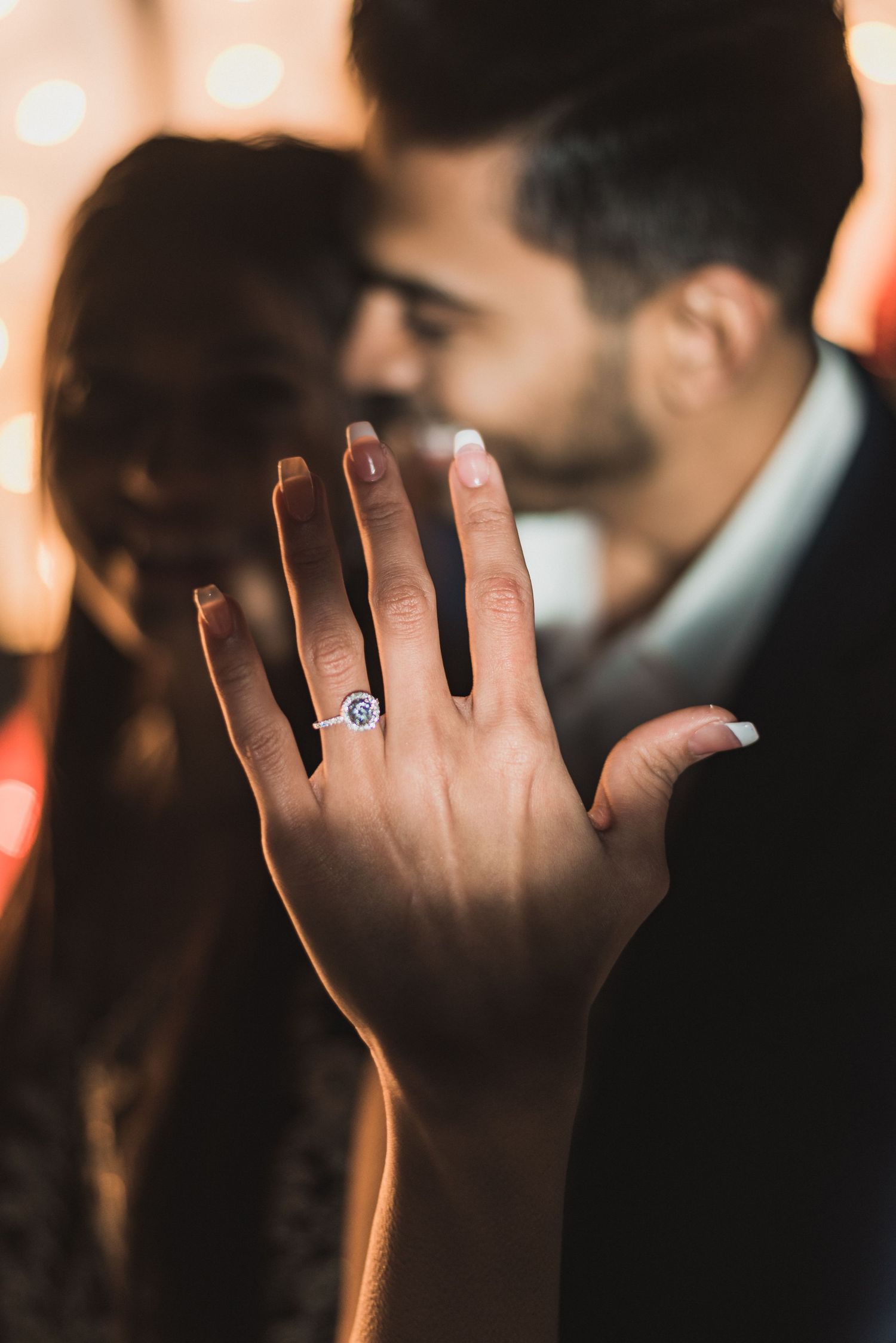 Close-up of hand showcasing an engagement ring with a sapphire stone.