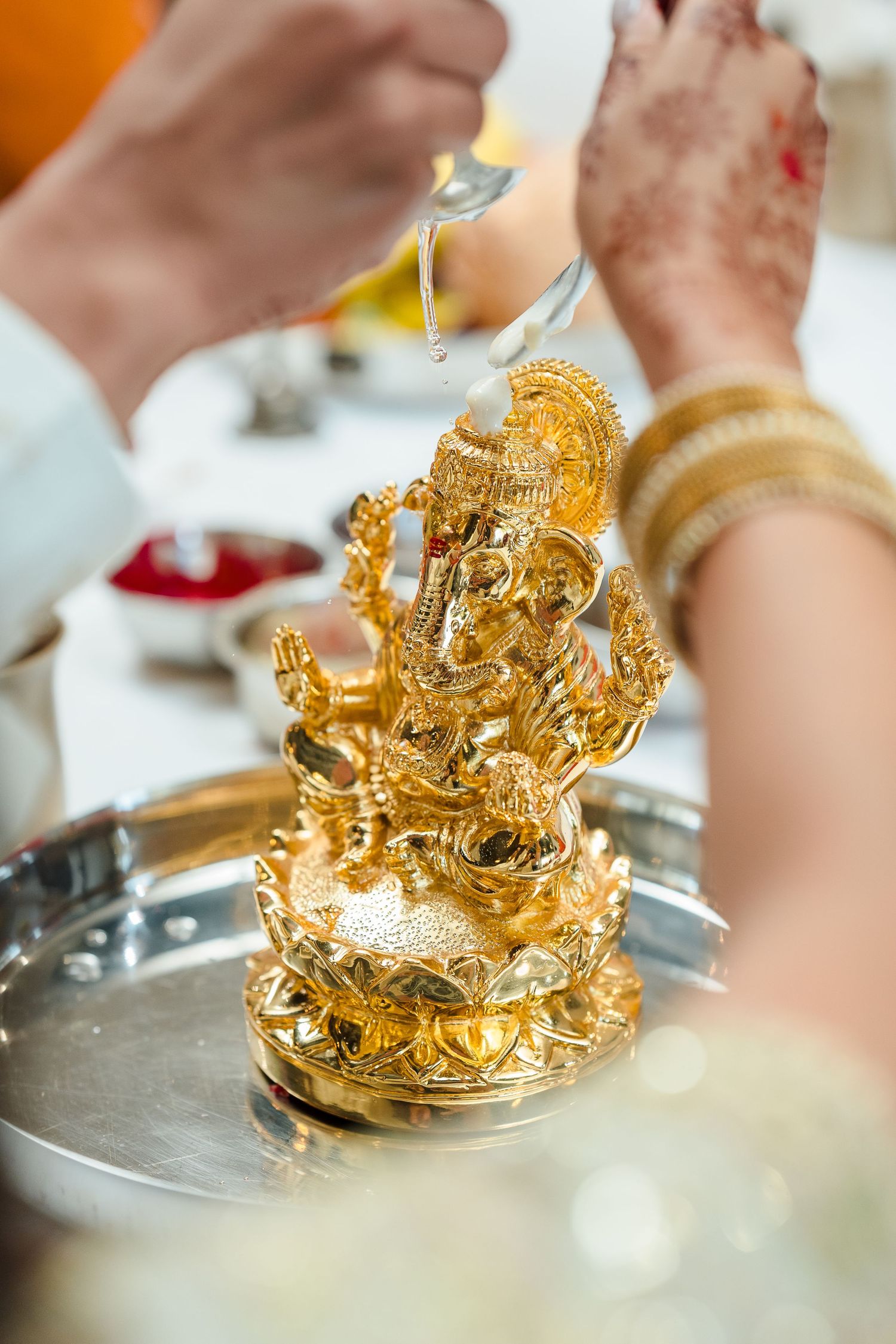 Golden Ganesh statue being ceremonially anointed with oil during a traditional ritual.