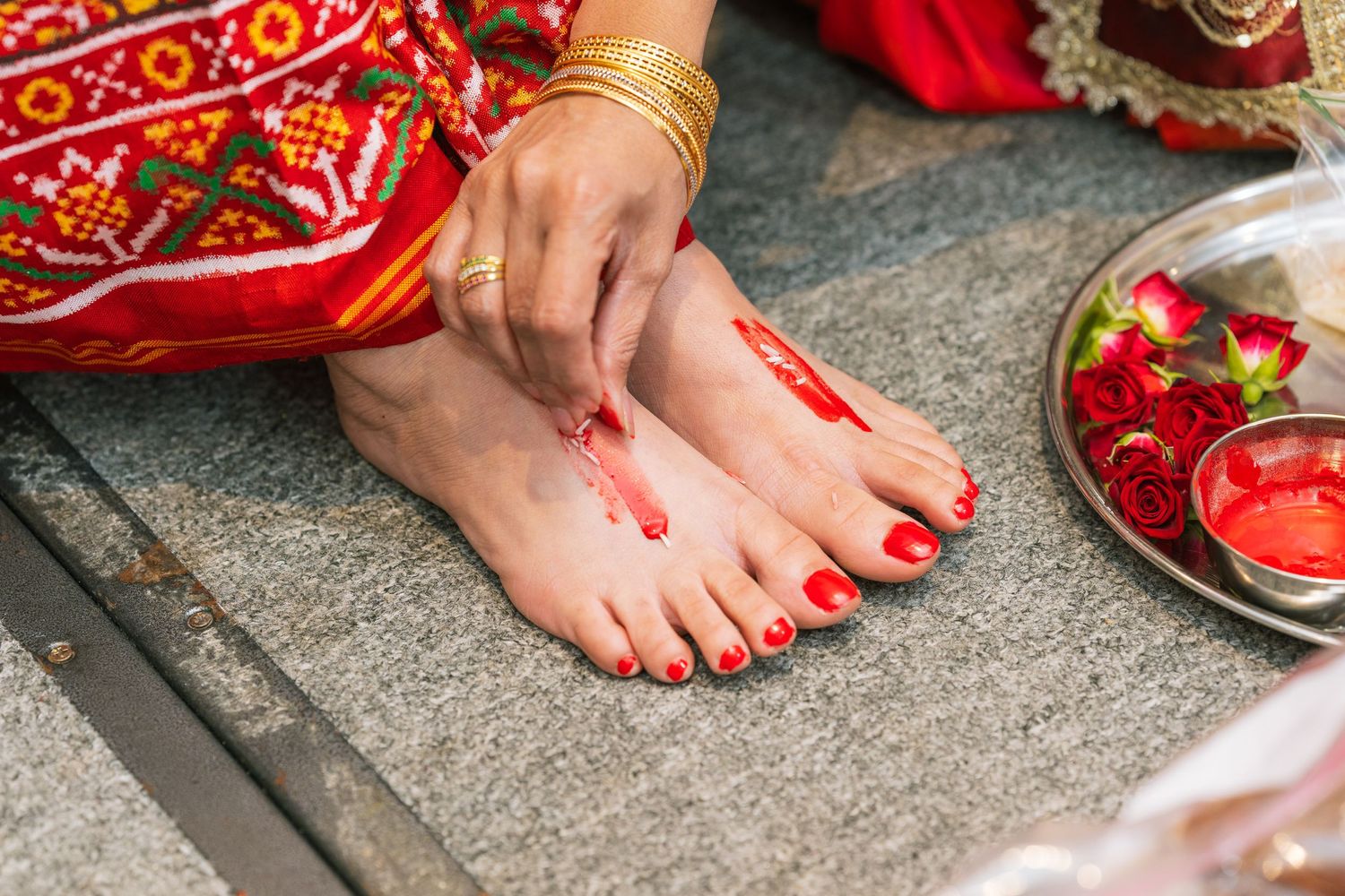 Traditional Indian ceremonial feet decoration with alta and red accessories.