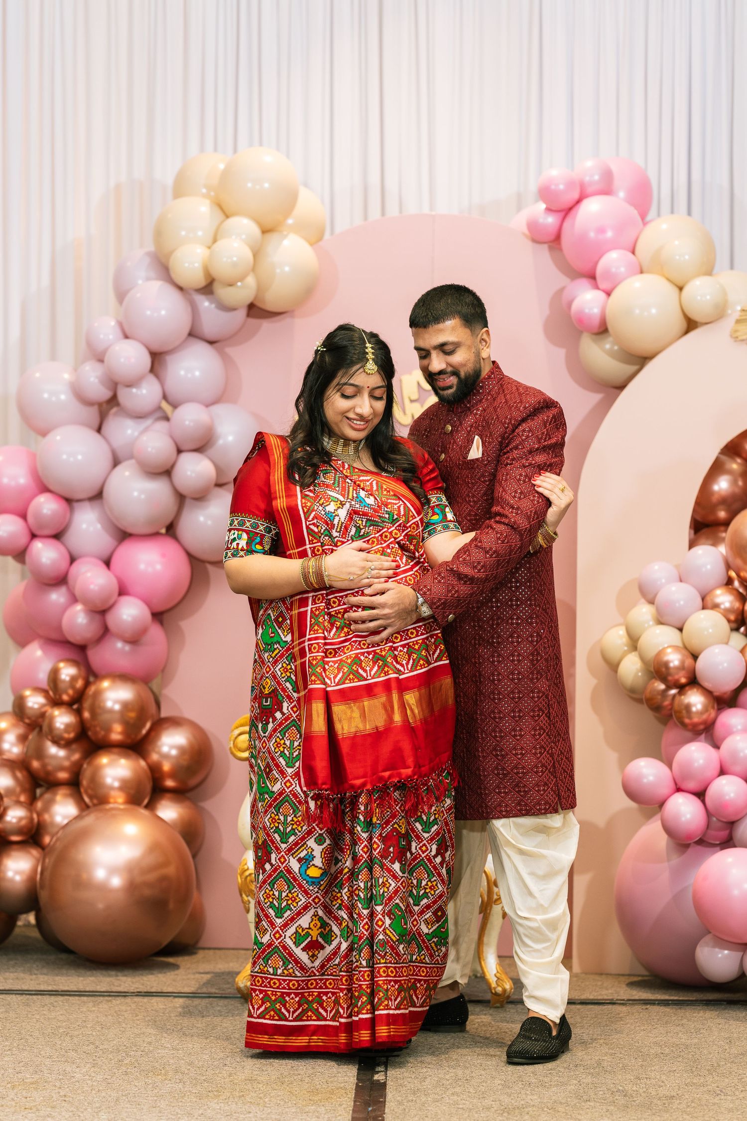 Elegant maternity photoshoot setup with pink and gold balloon arrangements.