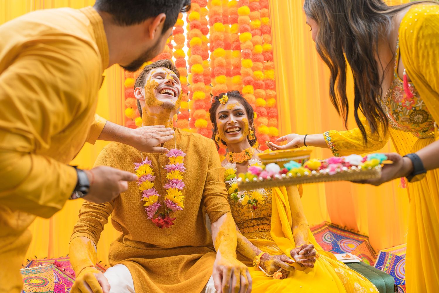Joyful celebration with people in yellow attire during Indian Haldi ceremony.