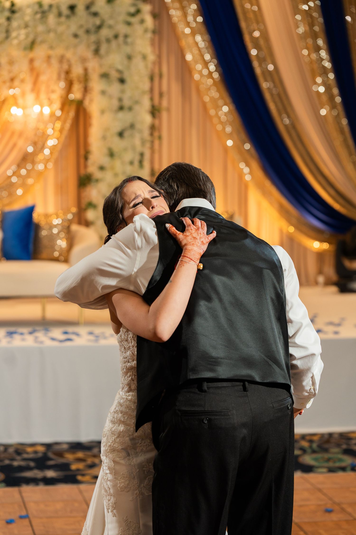 Couple sharing an intimate moment during their first dance at a wedding reception with elegant lighting and decor.