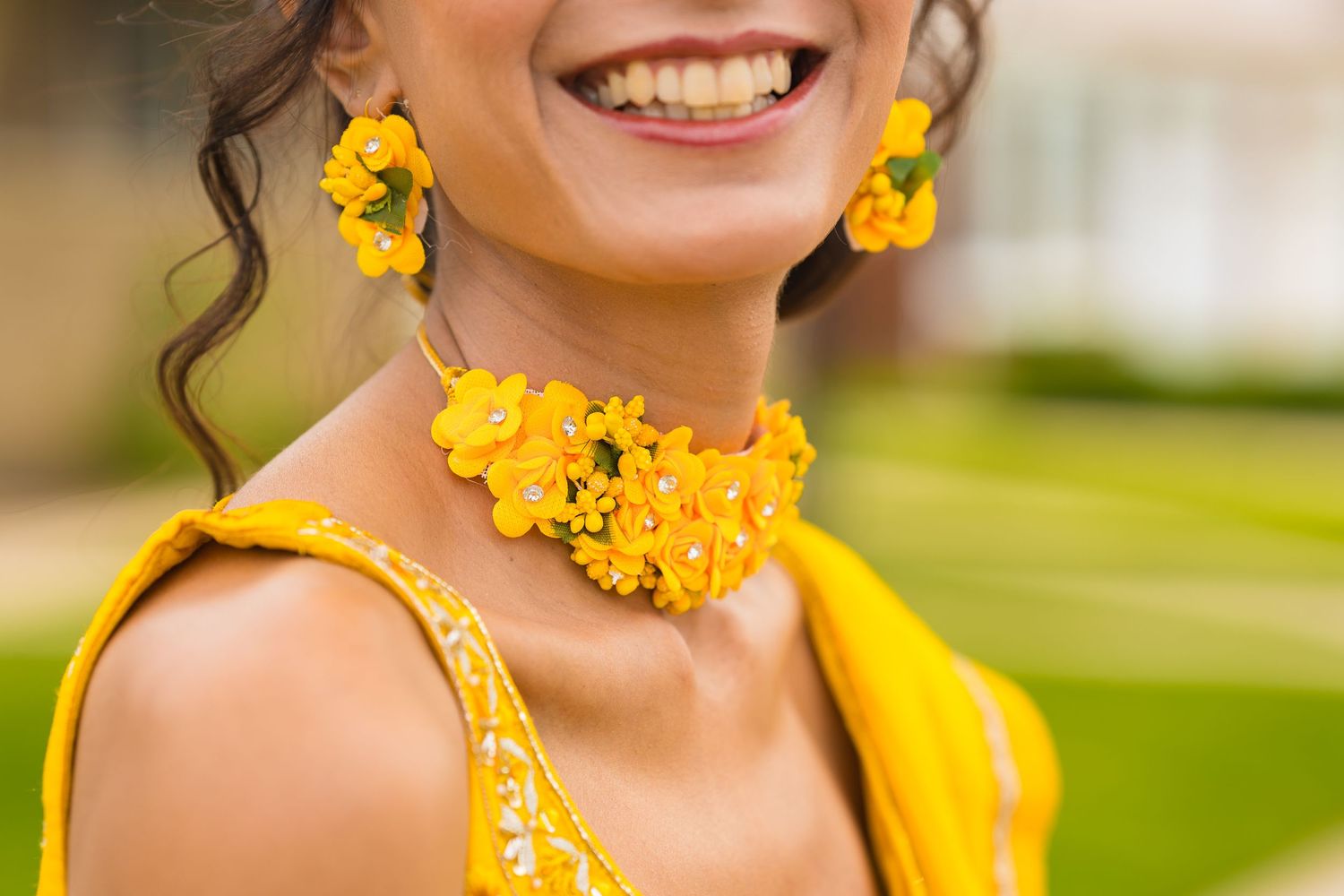 Close up of bright yellow floral jewelry set including earrings and necklace.