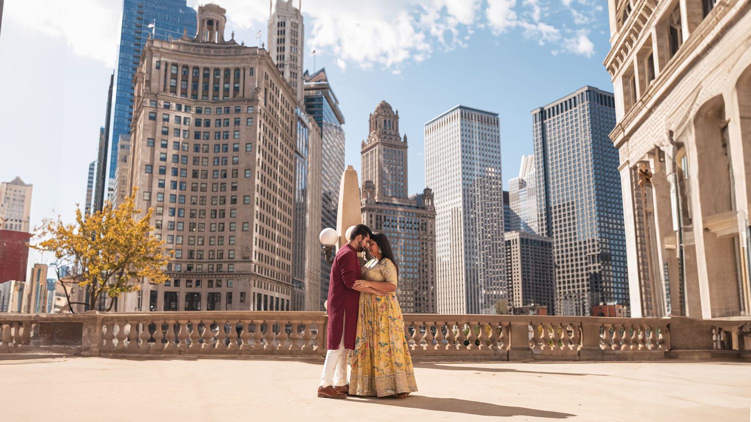 A couple in traditional attire posing against Chicago skyline architecture.